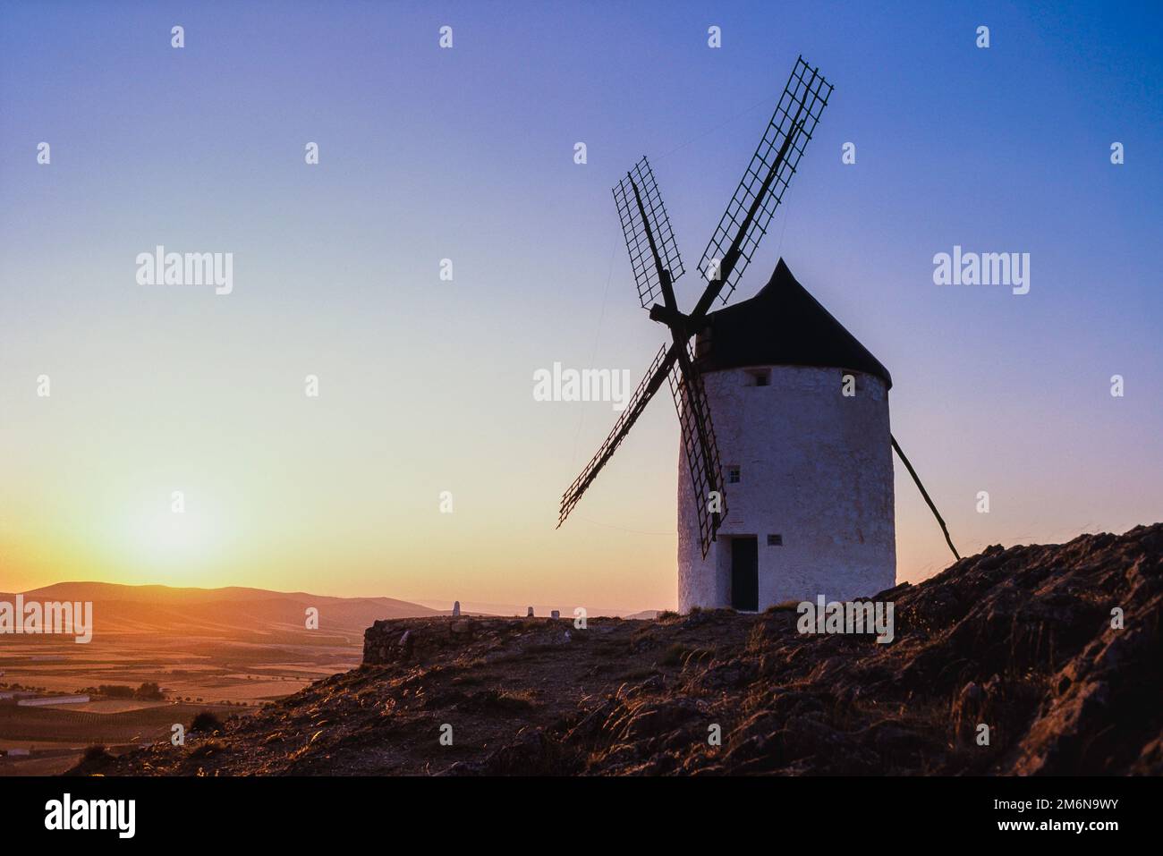 Ikonisches Spanien, Blick bei Sonnenuntergang auf eine historische Windmühle auf einem Hügel über der Ebene von La Mancha, Consuegra, Castilla-La Mancha, Spanien Stockfoto