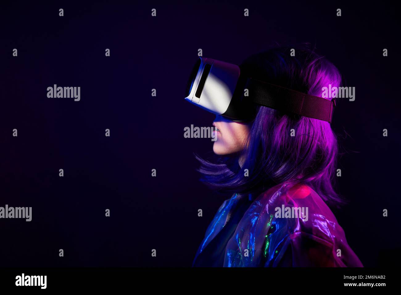 Eine Frau in Virtual-Reality-Brille in Neonfarben. Das Konzept der digitalen Technologie für Metaversum und Unterhaltung der Zukunft. Stockfoto
