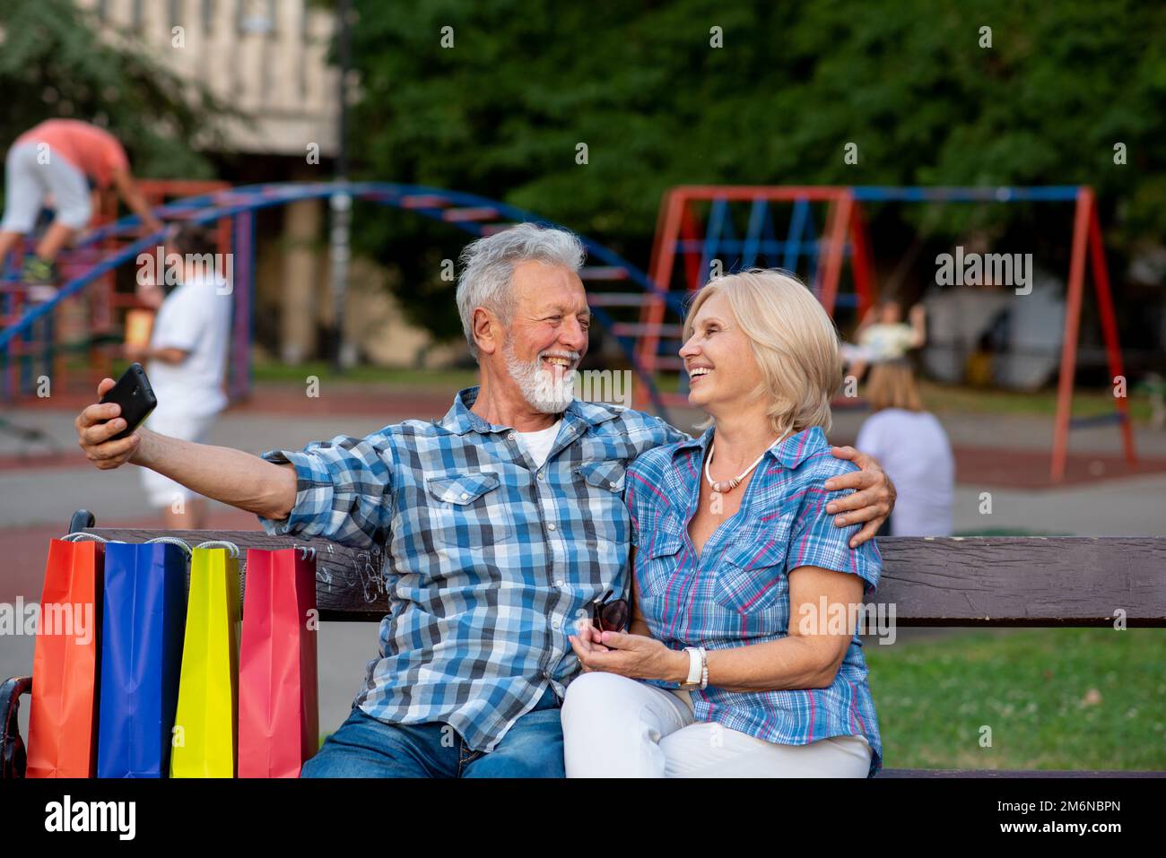Lächelndes Seniorenpaar, das Selfie in einem Park macht Stockfoto