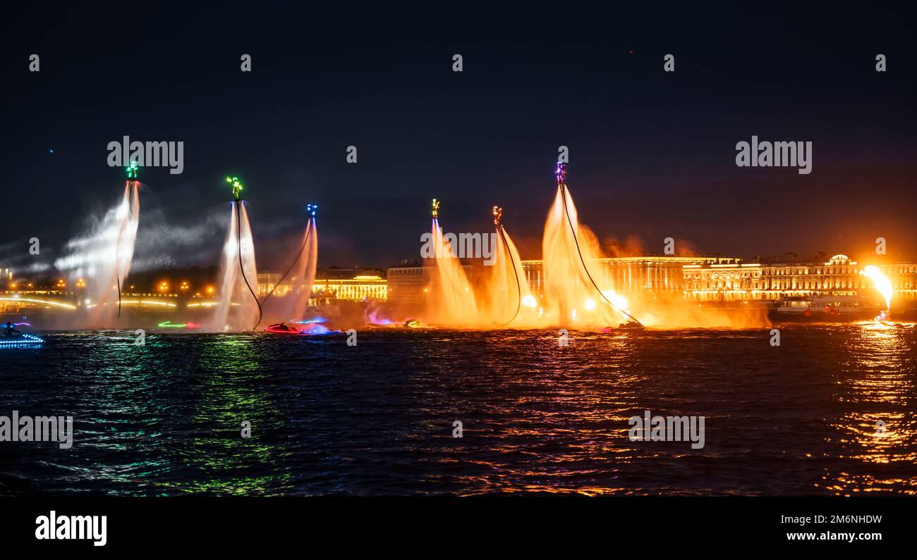 Viele Flyboarder und leuchtend verkleidete Jetski-Fahrer führen ihre Show an einem Feiertag im Zentrum von St. Petersburg bei Nacht Stockfoto