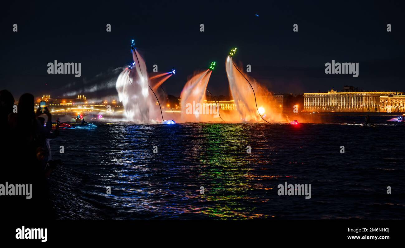 Viele Flyboarder und leuchtend verkleidete Jetski-Fahrer führen ihre Show an einem Feiertag im Zentrum von St. Petersburg bei Nacht Stockfoto