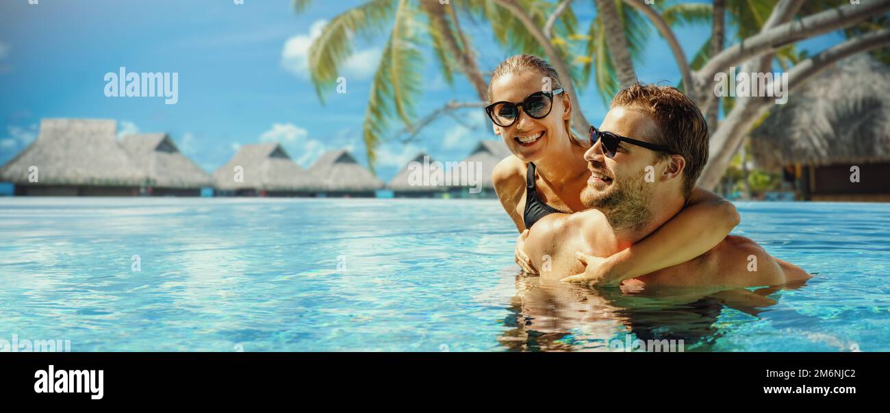 Sommerurlaub im tropischen Resort. Glückliches Paar, das sich im Swimmingpool mit Bungalows über dem Wasser im Hintergrund entspannen kann. Banner mit Kopierbereich Stockfoto