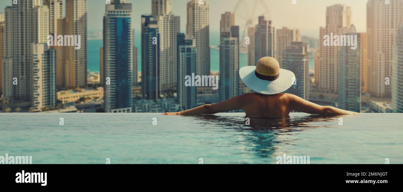 Frau genießt die Skyline des Yachthafens von Dubai vom luxuriösen Hotel Infinity Pool aus. Banner mit Kopierbereich Stockfoto