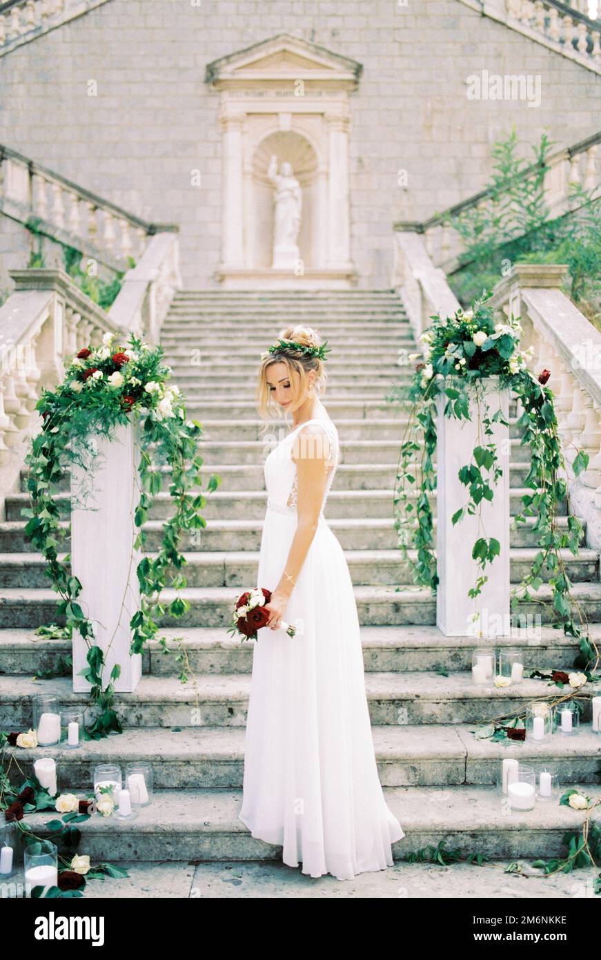 Die Braut mit Blumen steht auf den Stufen der Geburtskirche der Jungfrau in Prcanj Stockfoto