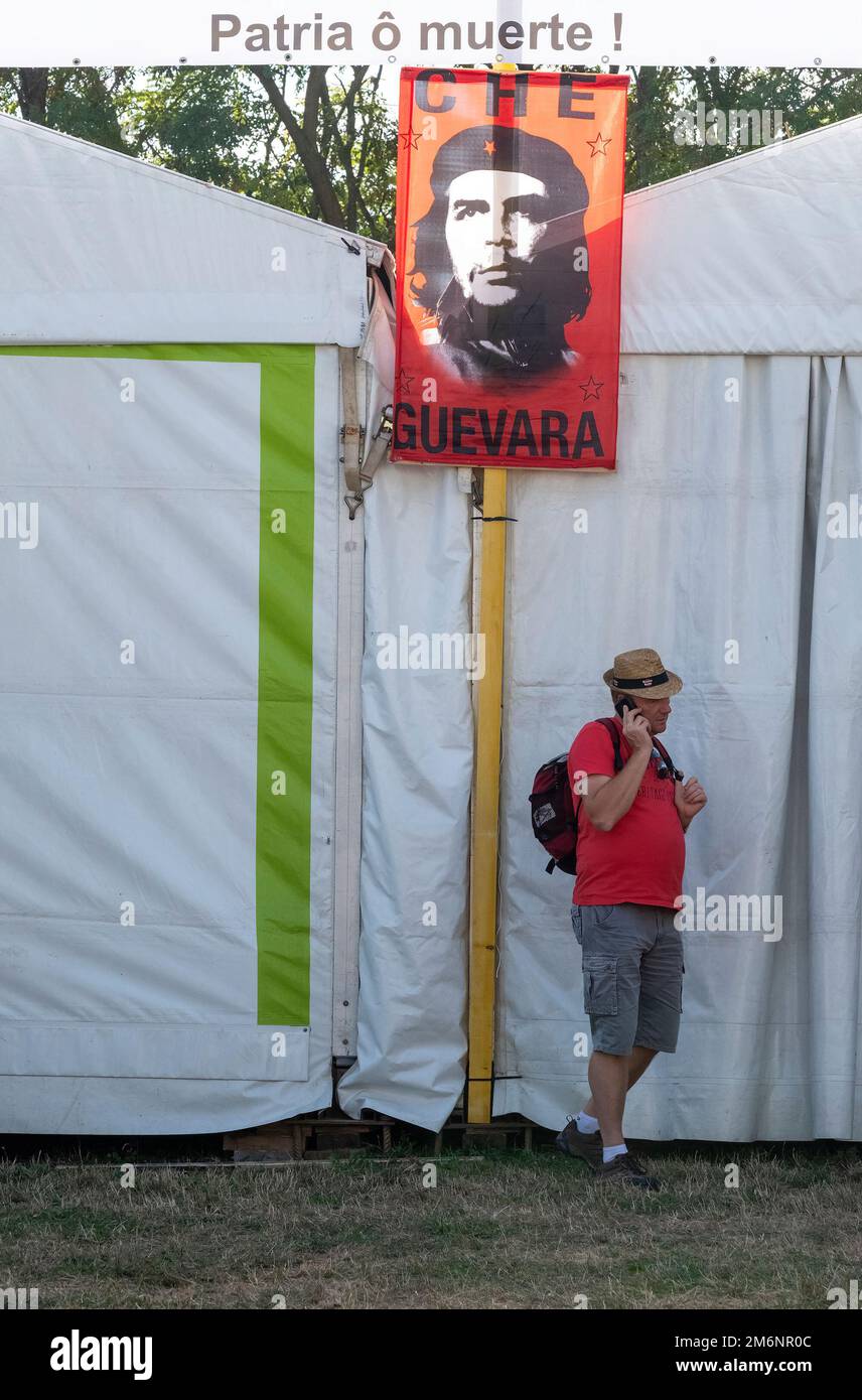Banner für Che Guevara und einen Mann, der anruft und ein T-Shirt in der gleichen Farbe wie das Banner trägt Stockfoto