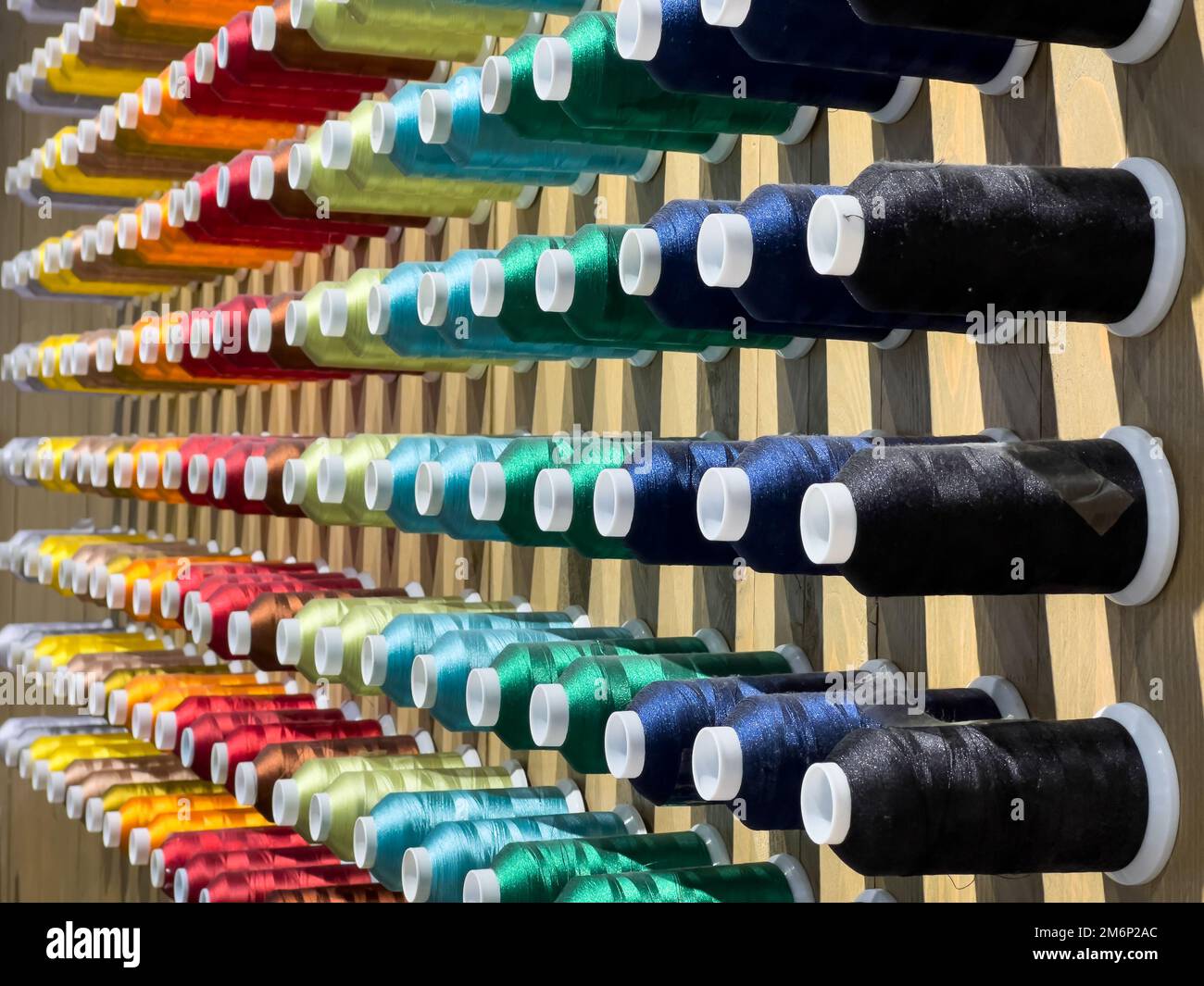 Diagonaler Nähwinkel farbige Fäden sind an der Wand im Muji Store in Johor, Malaysia, zu sehen. Stockfoto