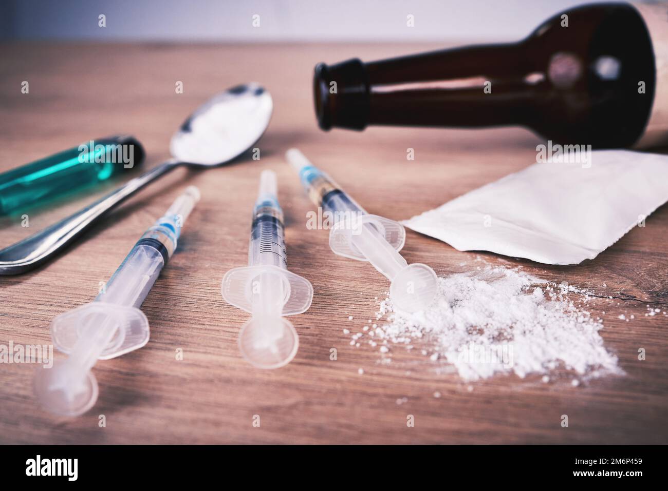 Pulver, Spritze und Medikamente mit Löffel auf dem Tisch bei Alkoholabhängigkeit, Drogenrehabilitation und Drogenmissbrauch. Medizin, illegale Produkte und Drogen Stockfoto