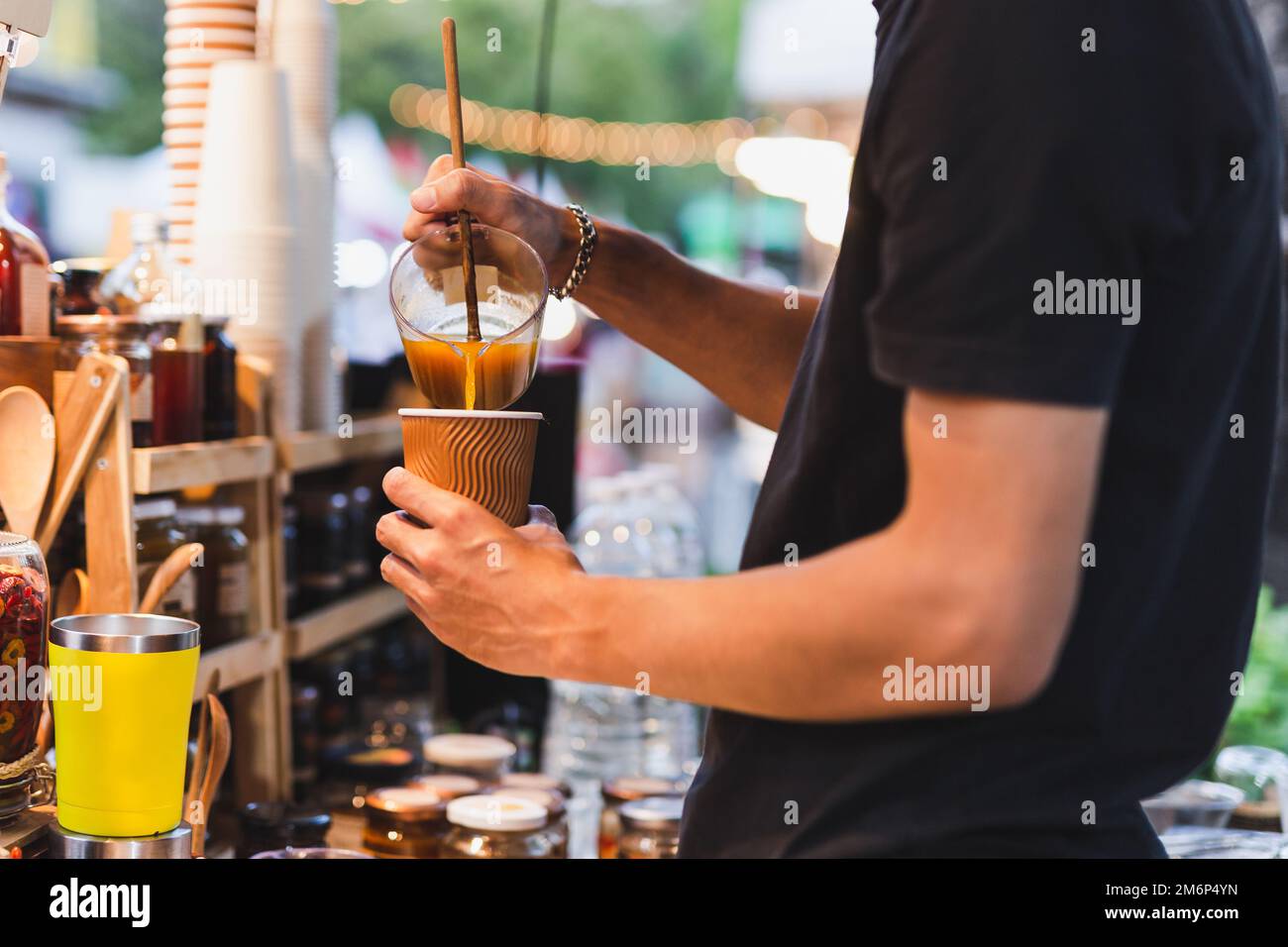 Mann Barista macht gesunden Latte mit Kurkuma Getränk an der Theke Bar Café im Freien. Stockfoto
