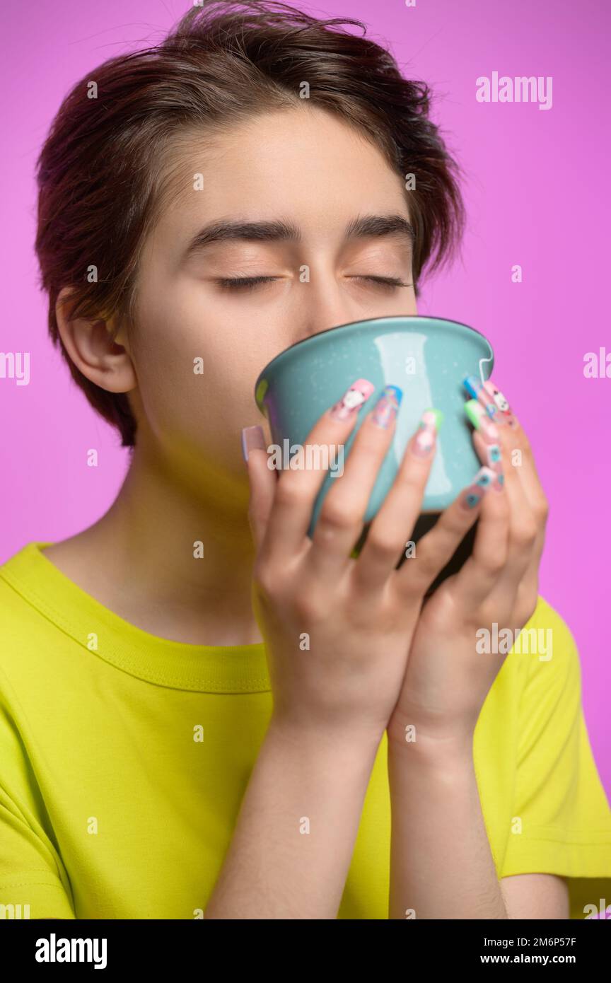 Gelangweiltes junges Mädchen, das morgens aus einer großen Tasse Tee oder Kaffee trinkt Stockfoto