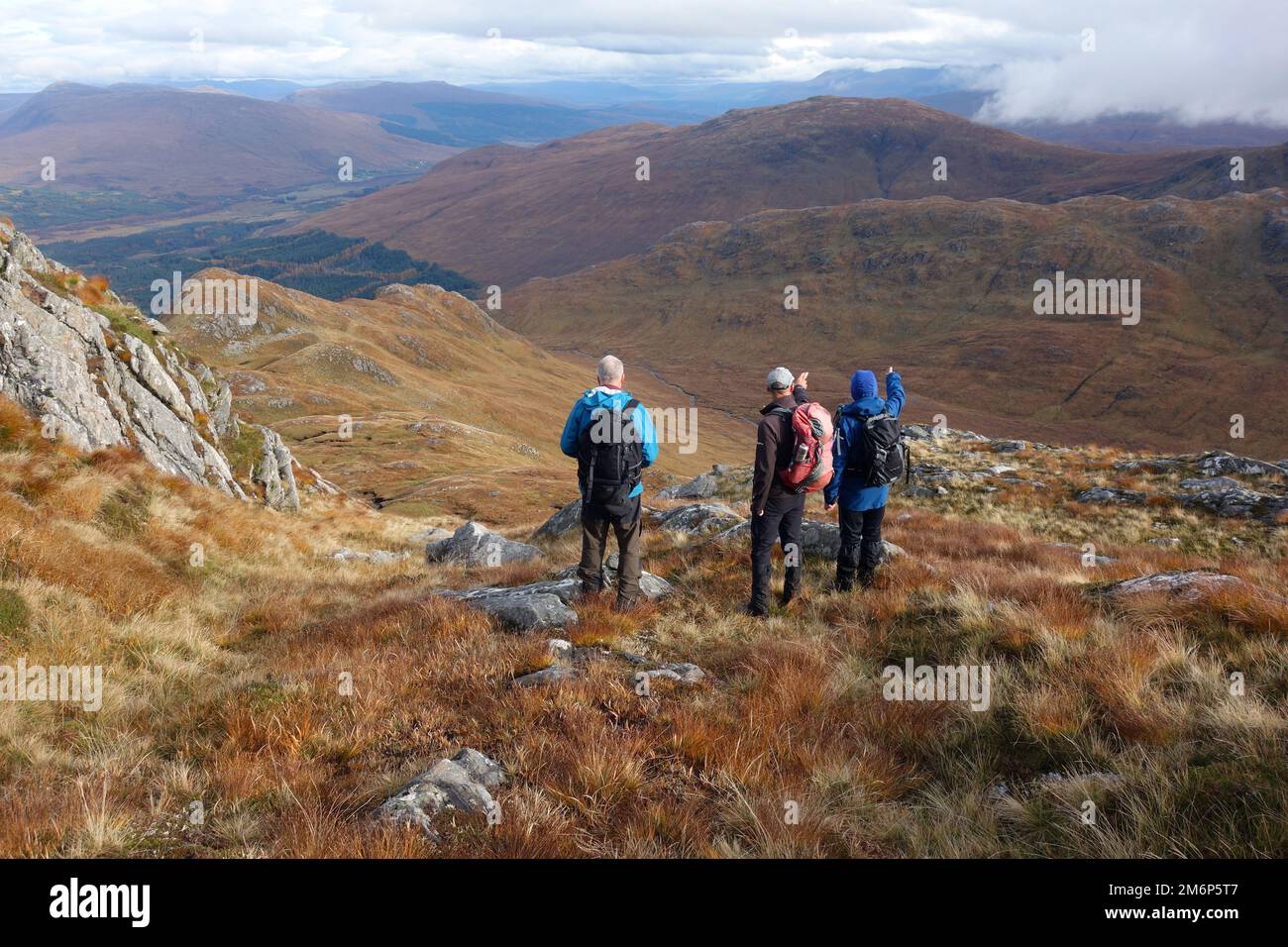 Three Men (Wanderer) stehen und zeigen auf dem Weg zum Scottish Mountain Corbett „Sgorr Craobh a' Chaorainn“ in der Nähe von Glenfinnan, Scottish Highlands. Stockfoto