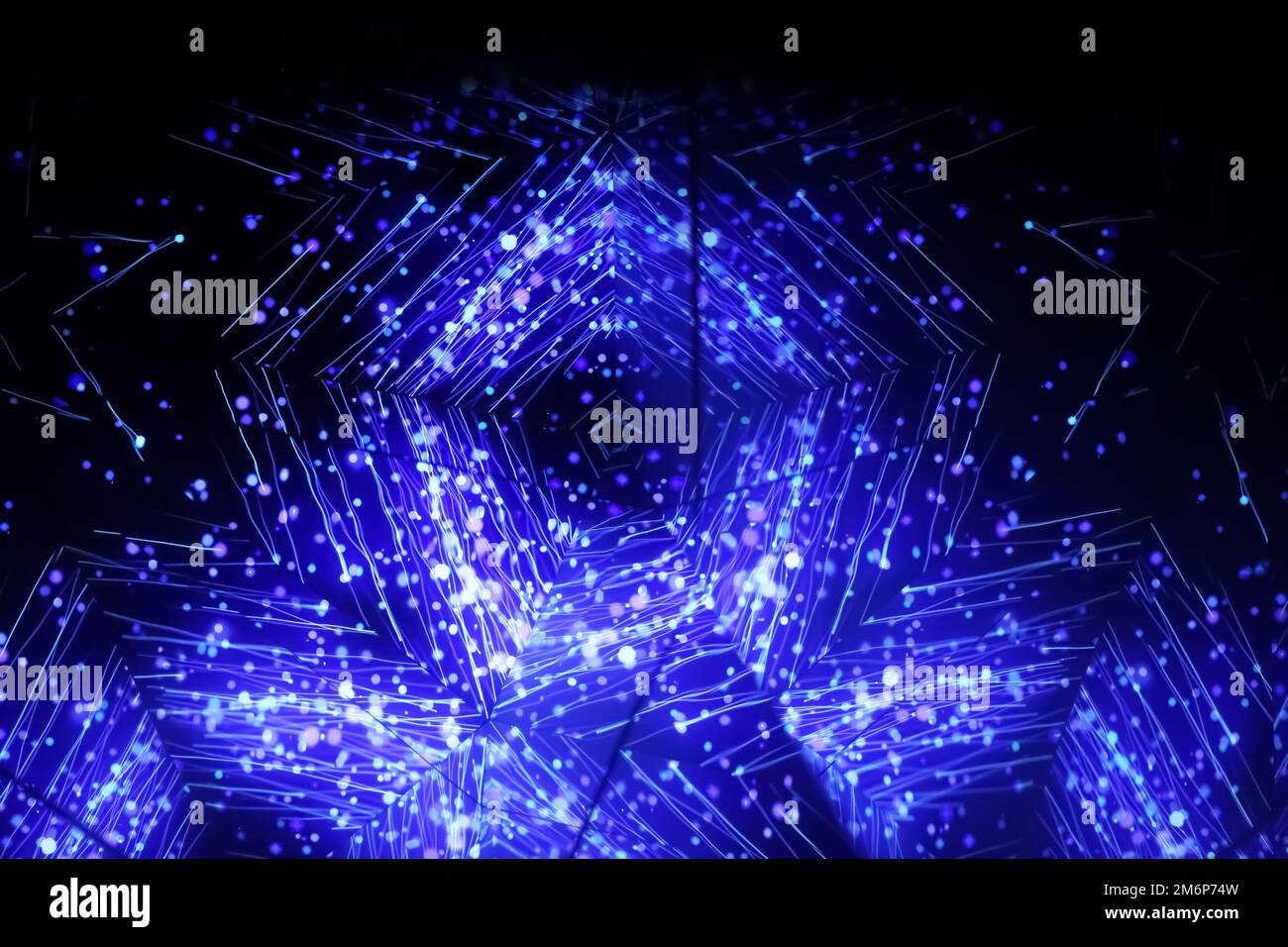 Blaues Kaleidoskop-Ornament. Karussell-Kaleidoskop. Helles Neonmuster auf dunklem Hintergrund. Horizontales unscharfes Bild Stockfoto