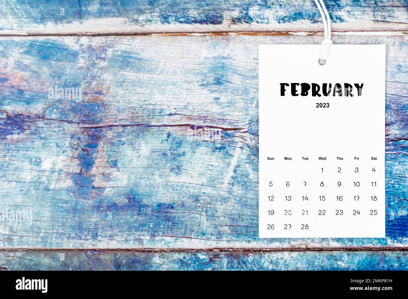 Kalenderseite vom Februar 2023 mit weißem Seil auf altblauem Holzhintergrund. Stockfoto