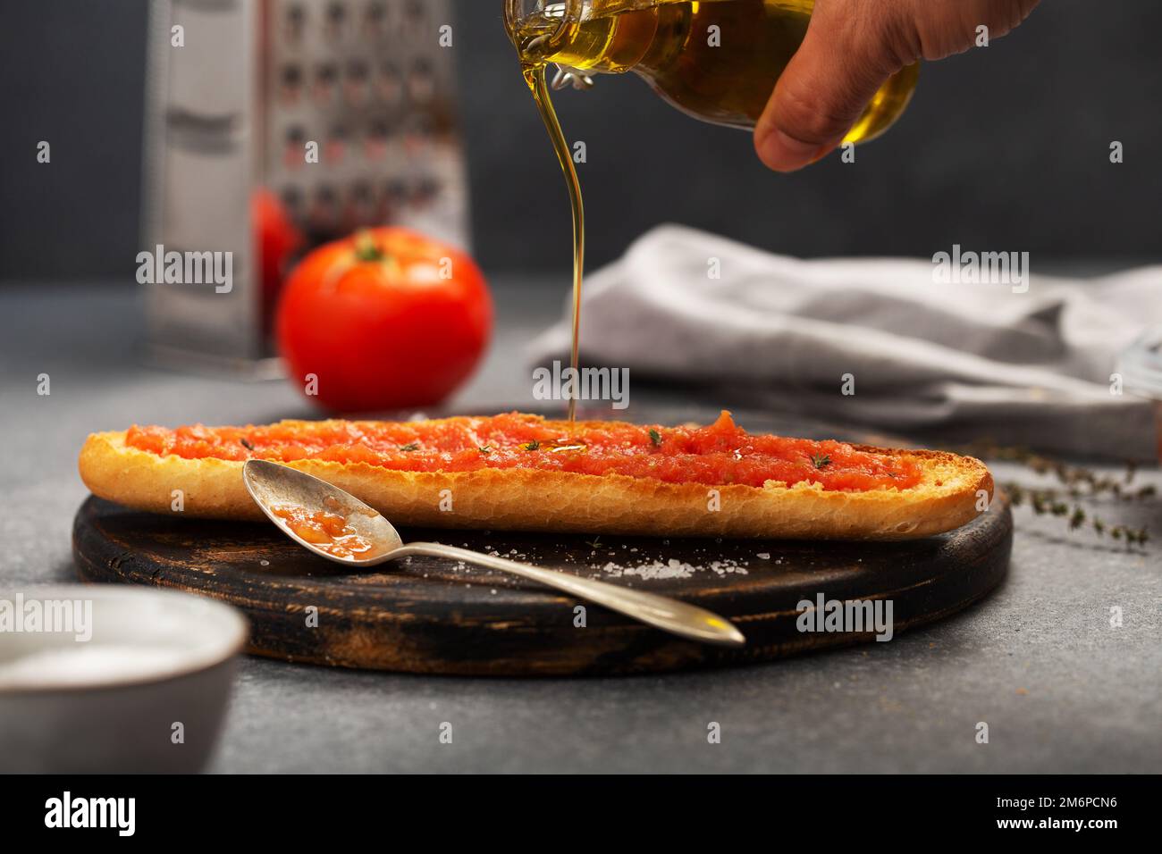 Olivenöl wird auf Brot gegossen, auf dem geriebenes Tomat aufgetragen wird. Traditionelles spanisches Frühstück Stockfoto