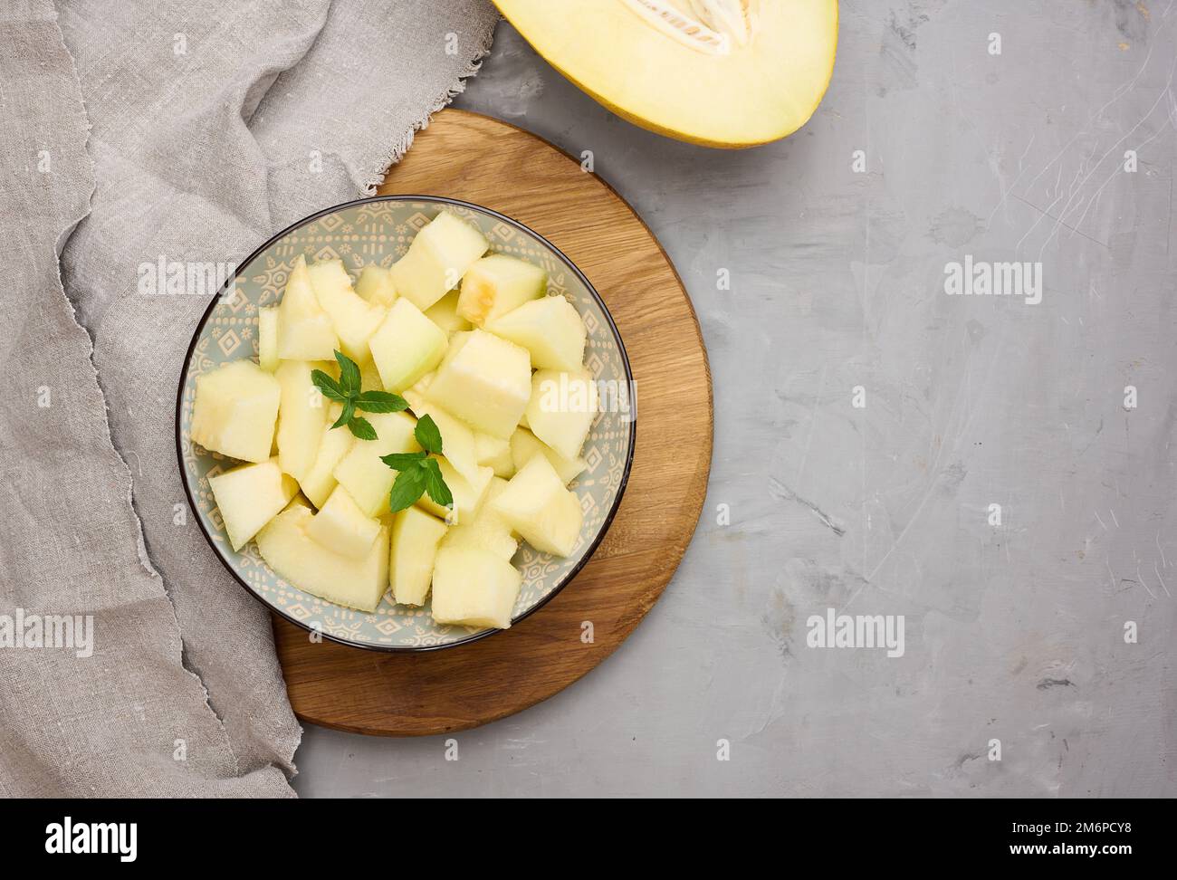 In Scheiben geschnittene Melonenstücke auf einem runden grauen Teller auf dem Tisch Stockfoto