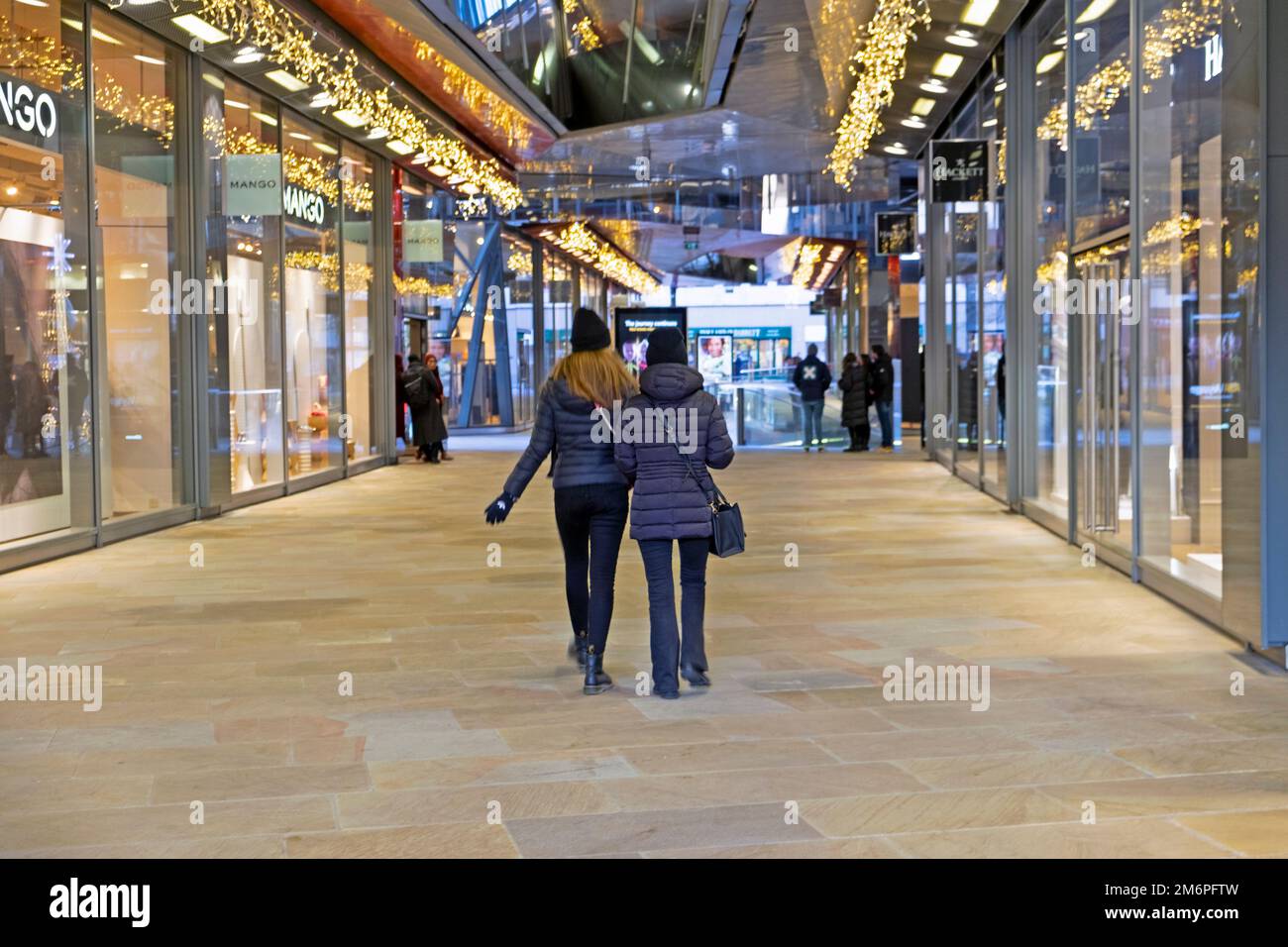 Rückansicht zwei junge weibliche Kauffrauen, die in einem New Change Einkaufszentrum in der City of London, England, KATHY DEWITT, an Geschäften vorbeigehen Stockfoto