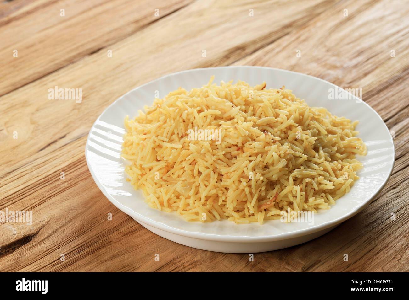 Aloo ki Tahari, köstlicher indischer Basmati-Reis mit Kartoffeln und grünen Erbsen. Auf Einem Holztisch Stockfoto
