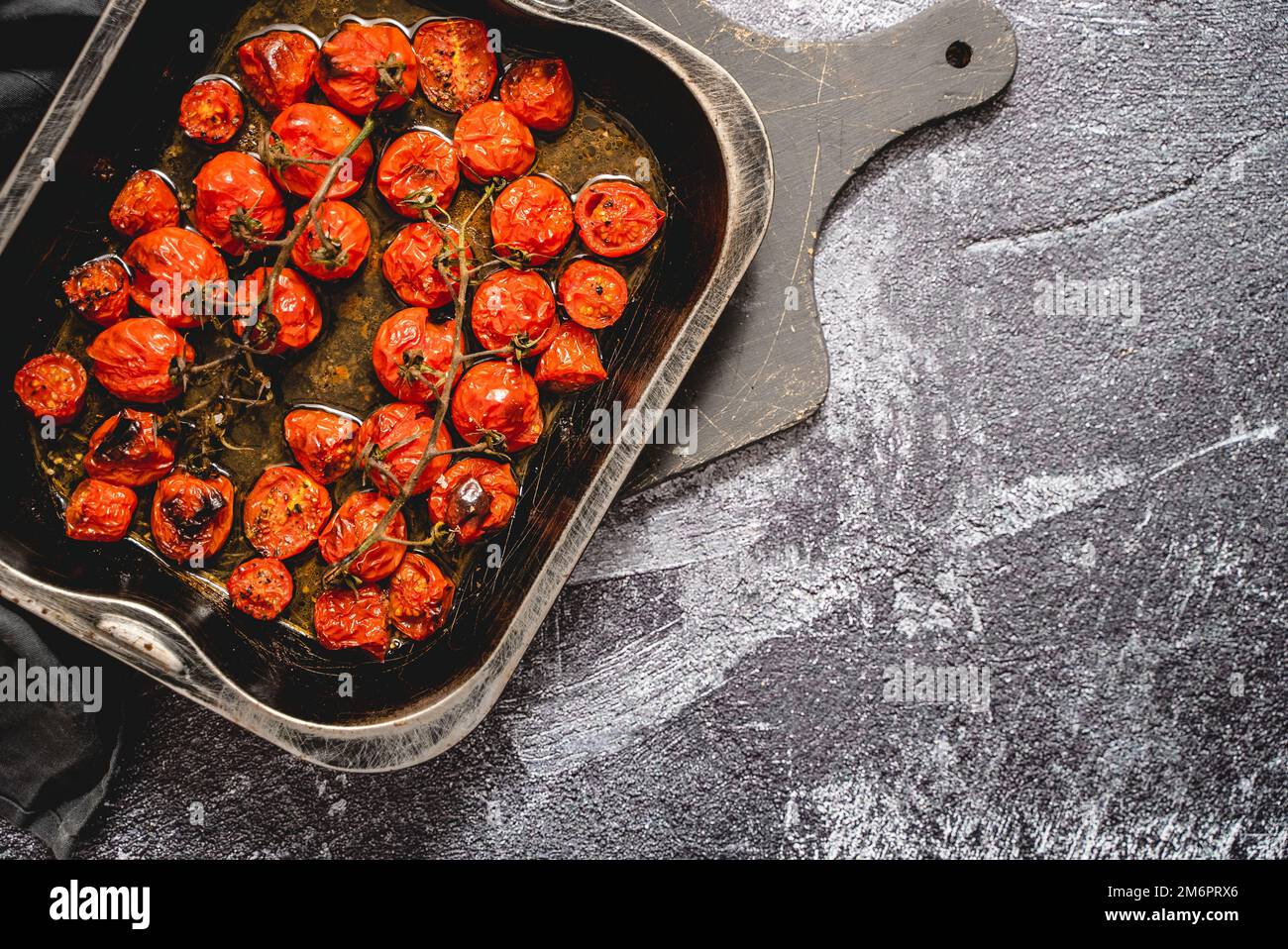 Tablett mit gerösteten roten Kirschtomaten mit Knoblauch, Kräutern und Oliven Stockfoto