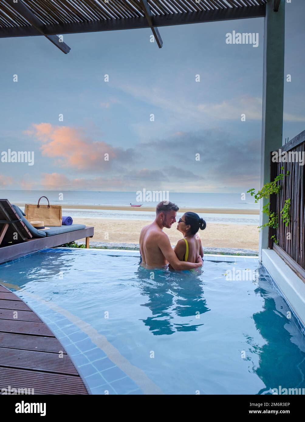 Ein Paar in einer Luxusvilla, die sich im Pool mit Blick auf das Meer und den Strand bei Sonnenuntergang Vergnügen Stockfoto