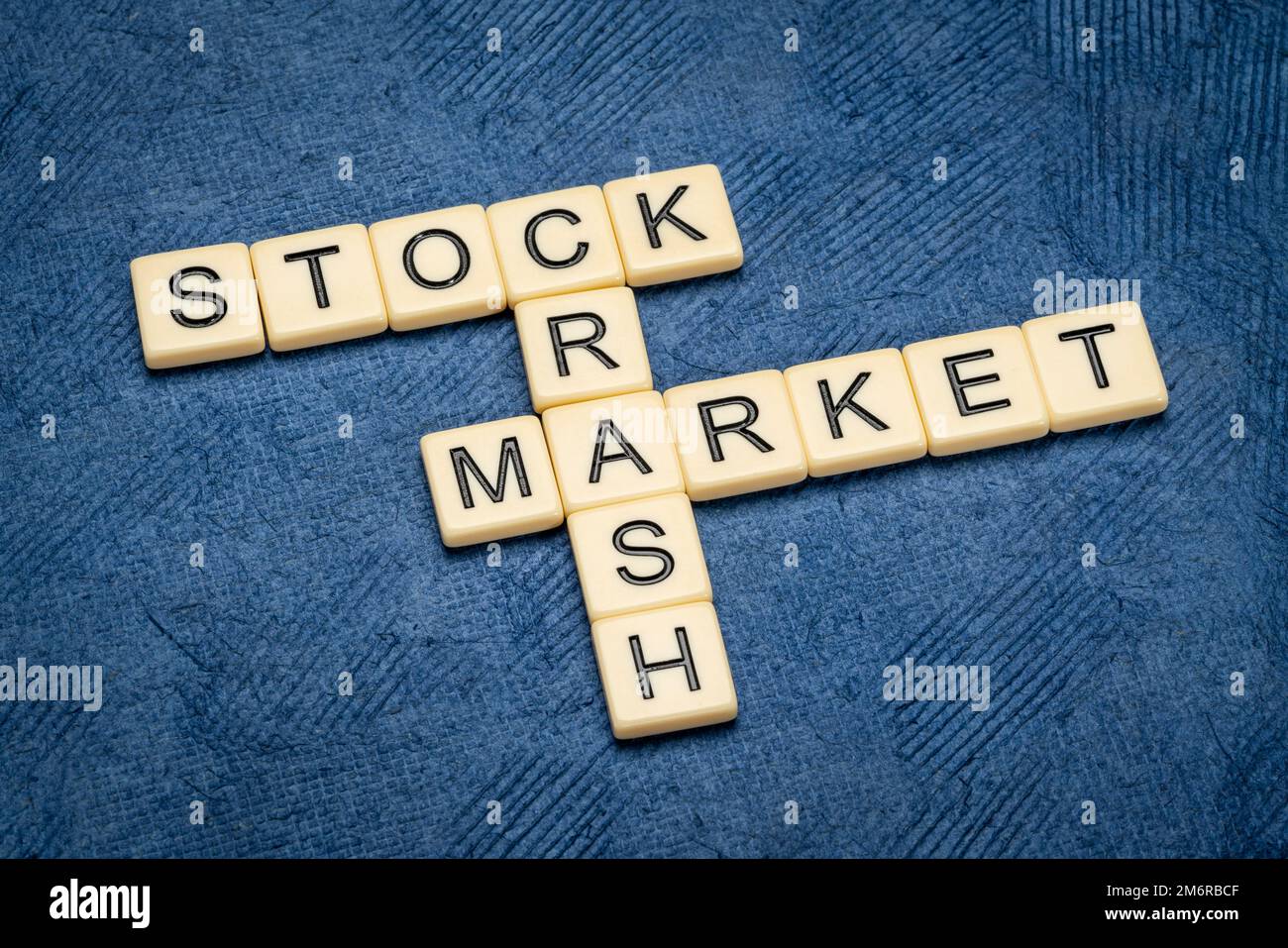 Börsencrash Kreuzworträtsel in elfenbeinfarbenen Buchstabensteinen gegen Texturpapier, Wirtschaft und Rezessionskonzept Stockfoto