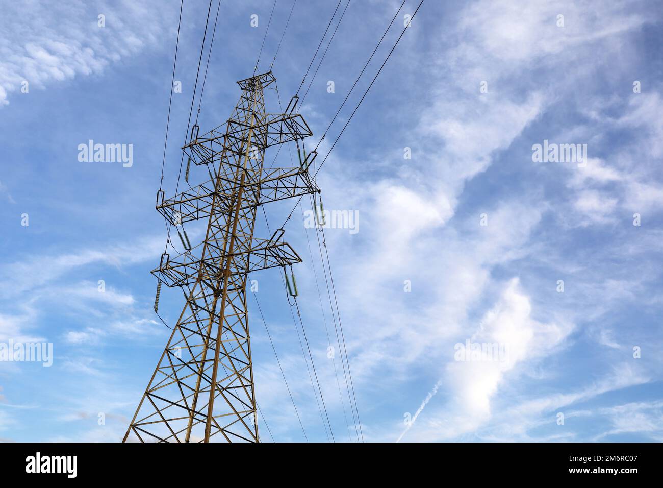 Hochspannungsturm mit elektrischen Drähten am blauen Himmel mit weißen Wolken. Stromübertragungsleitungen, Stromversorgungskonzept Stockfoto