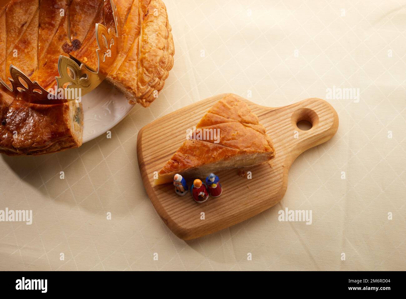 King Cake oder Galette des rois auf Französisch. Epiphanienkuchen mit goldener Papierkrone und kleiner Keramikfigur Stockfoto