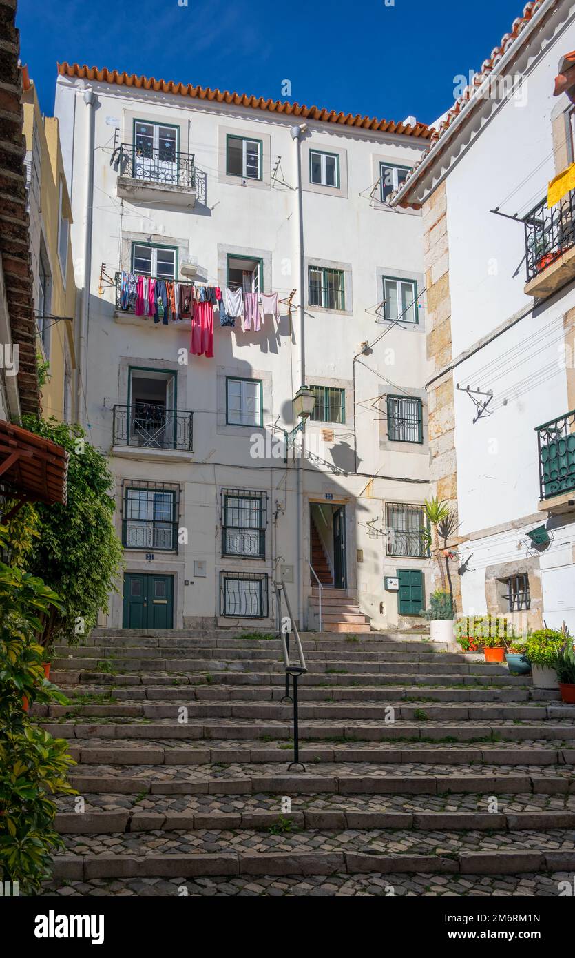 Wunderschöne, enge Kopfsteinpflasterstraßen zusammen mit traditionellen bunten Häusern, Cafés und Restaurants im Alfama-Viertel, Lissabon, Portugal. Stockfoto