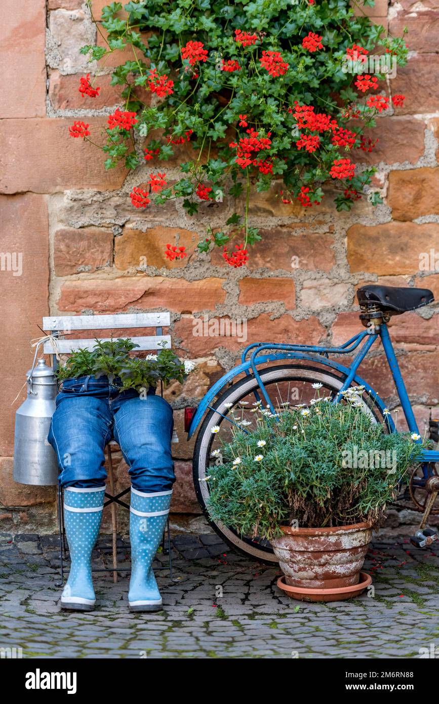 Seltsame Dekoration an einer Haustr, blaue Jeans Hose in Gummistiefeln mit  Blumentopf, Geranien, altes Fahrrad, Altstadt, Ortenberg, Wetterau  Stockfotografie - Alamy