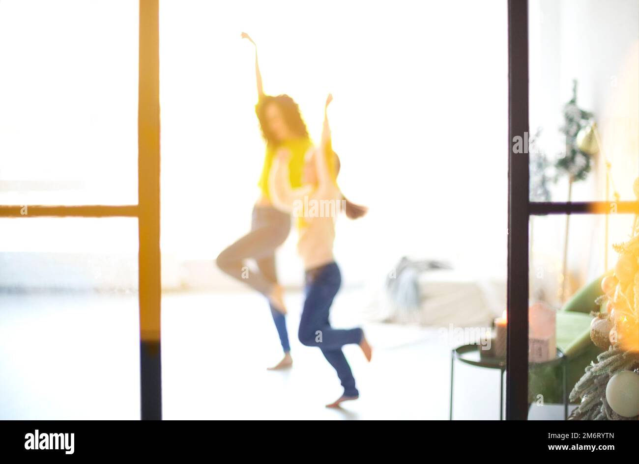 Glückliche Familienmutter und kleine Tochter, die Händchen hält und in einem hellen, sonnigen Raum tanzt Stockfoto