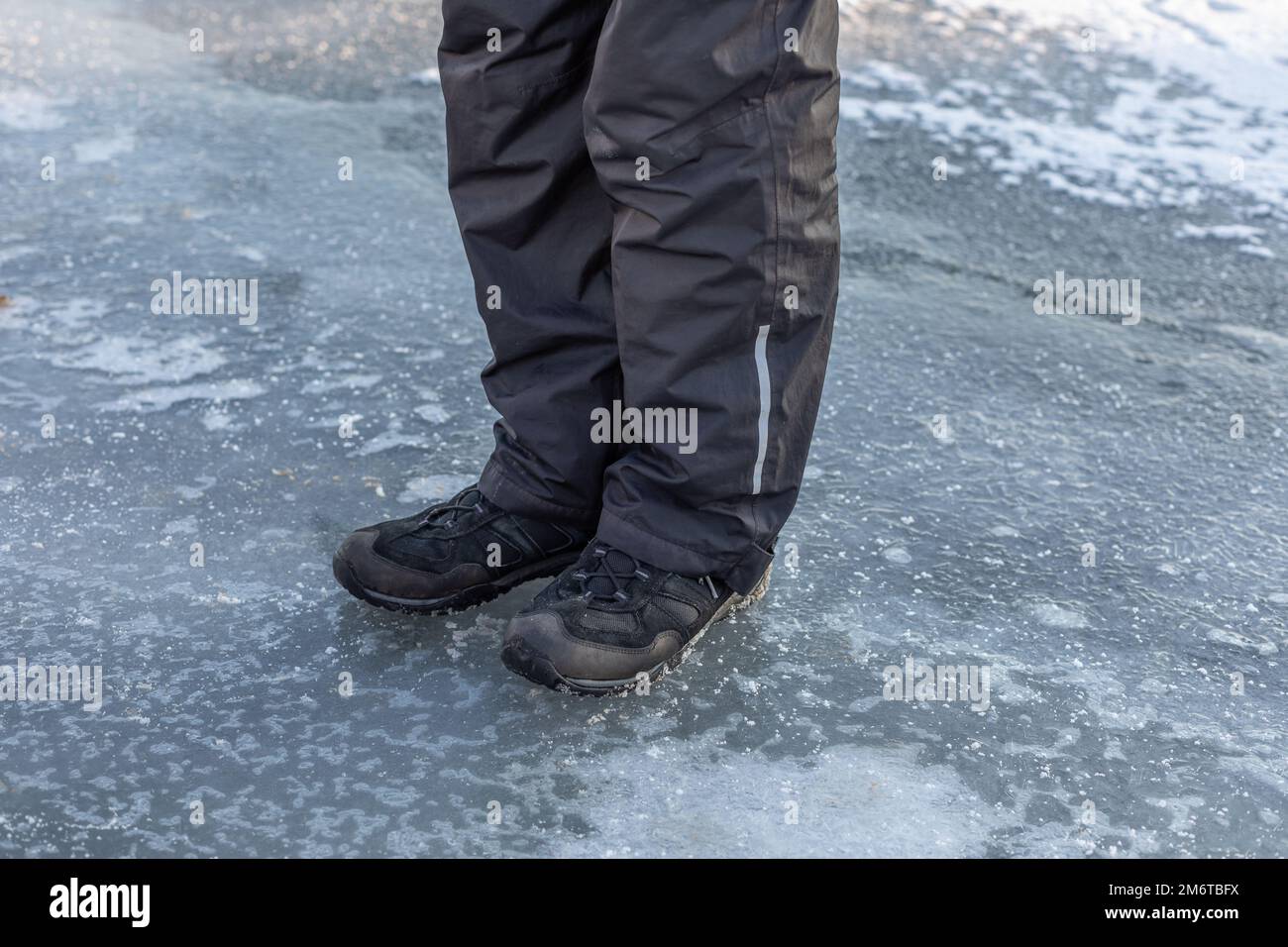 Der Mann steht auf dem dünnen Eis eines gefrorenen Sees Stockfoto
