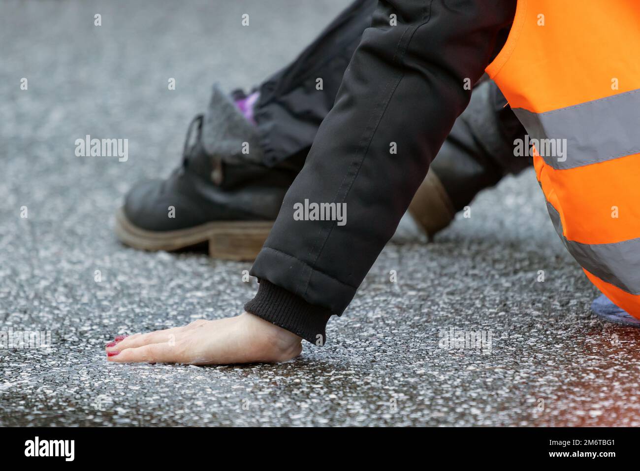 Eine Klimaaktivistin klebte sich mit Sekundenkleber auf den Asphalt Stockfoto