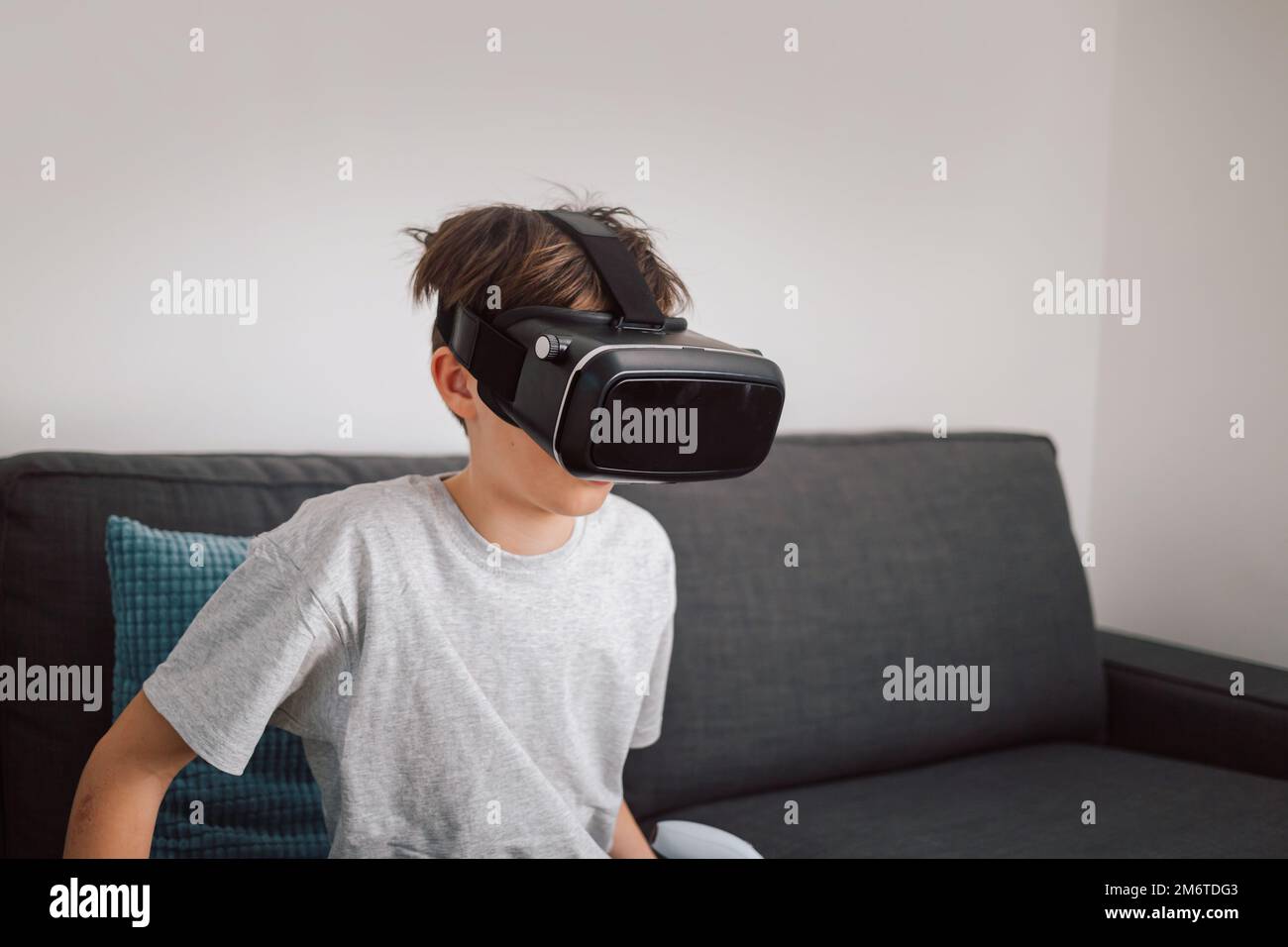 Männliches Kind aus Kaukasien, das ein Virtual-Reality-Headset aufsetzt und überrascht von einer virtuellen Welt aussieht Stockfoto