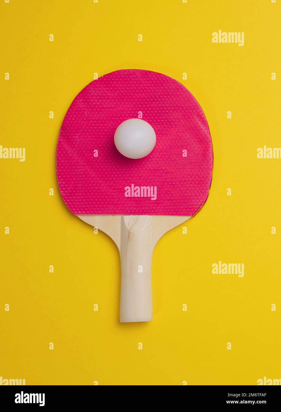 Tischtennisschläger aus Holz und Kunststoffball auf gelbem Hintergrund Stockfoto