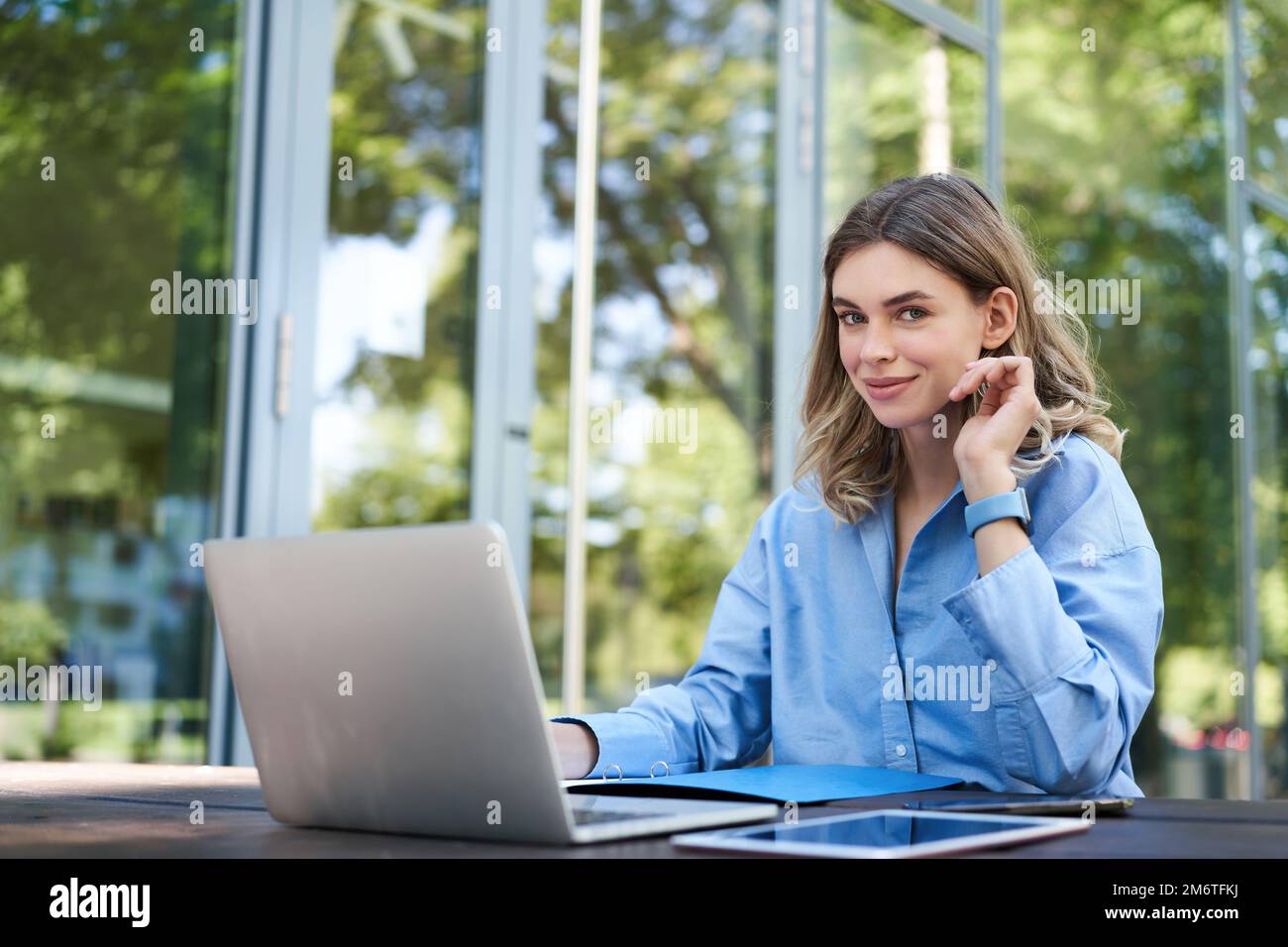 Porträt einer Geschäftsfrau, die an der frischen Luft arbeitet. Weibliche Geschäftsfrau mit Laptop, die außerhalb des Bürogebäudes sitzt und Computer verwendet Stockfoto