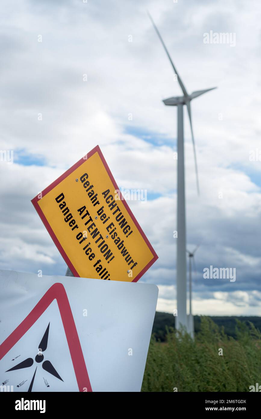 Windturbinen mit einem Vorsichtshinweis, der vor den Gefahren warnt, die sich der Turbine nähern Stockfoto