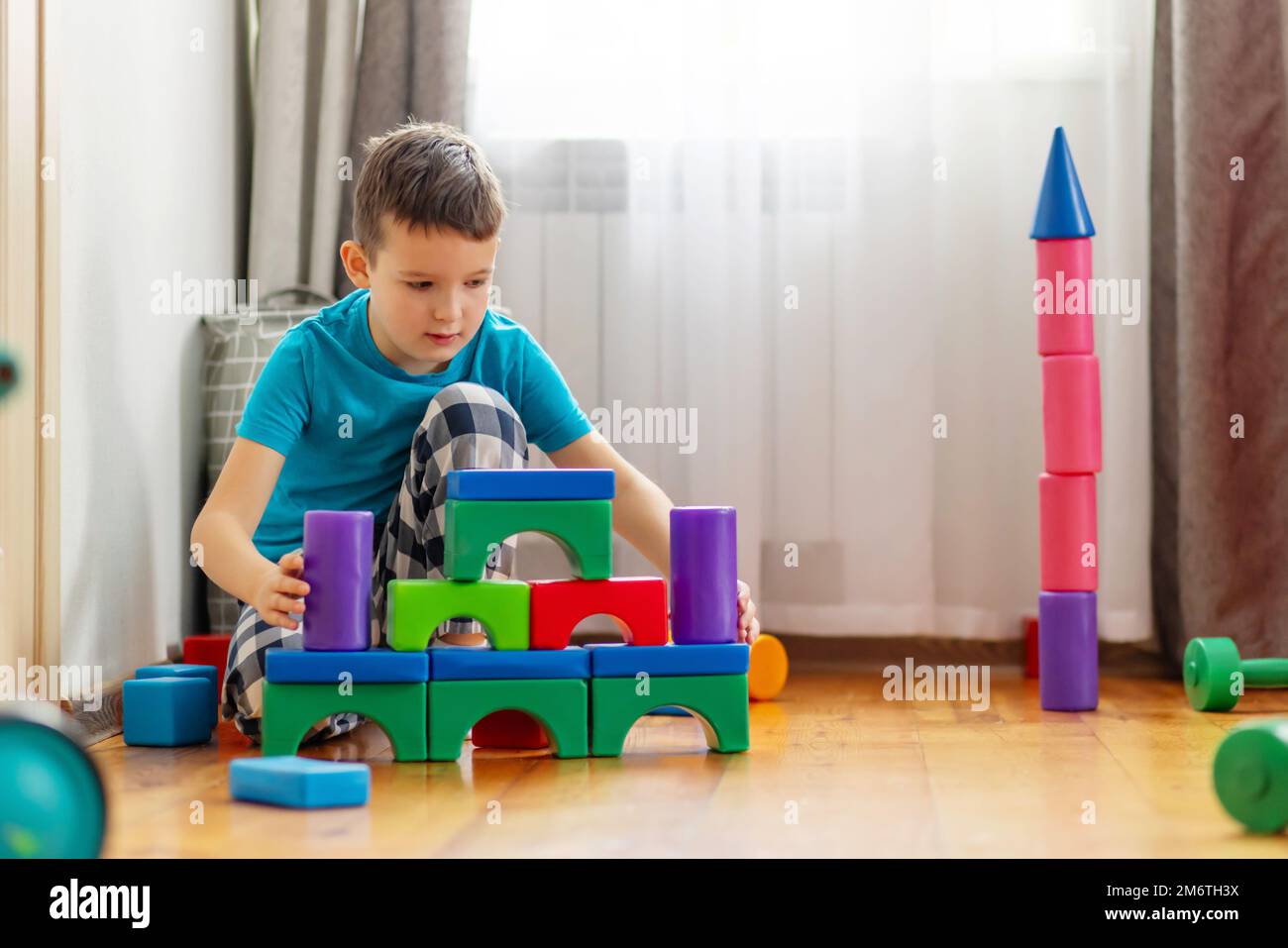 Niedliches kleines Kind, das mit bunten Plastikspielzeugen oder Bausteinen spielt Stockfoto