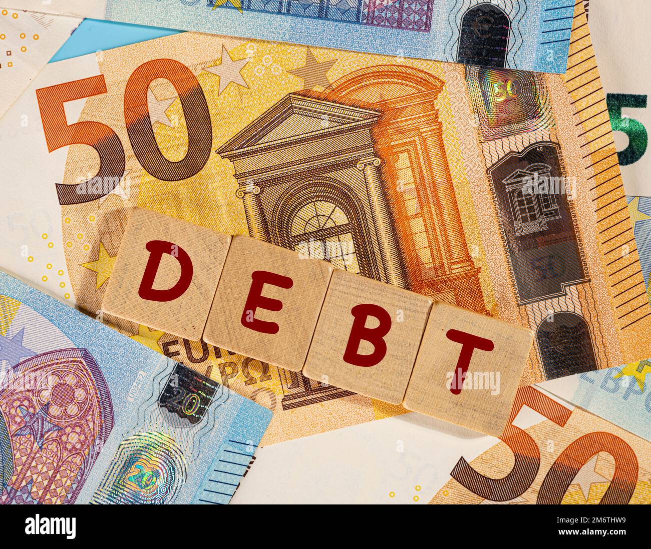 Das WORT "SCHULDEN" über einigen Euro-Banknoten Stockfoto