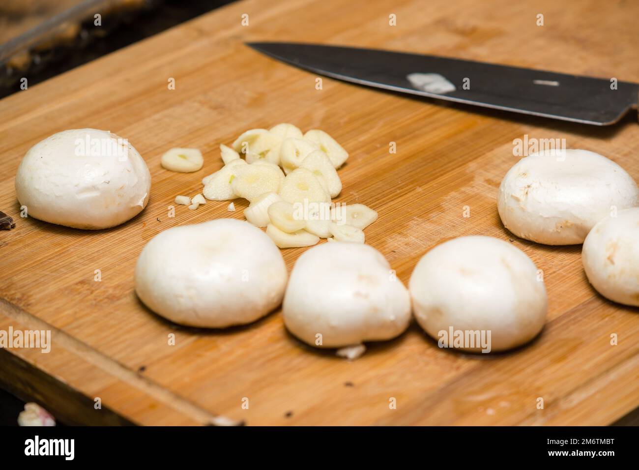Gehackter Knoblauch, Pilze auf einem Schneidebrett, bereit zum Kochen Stockfoto
