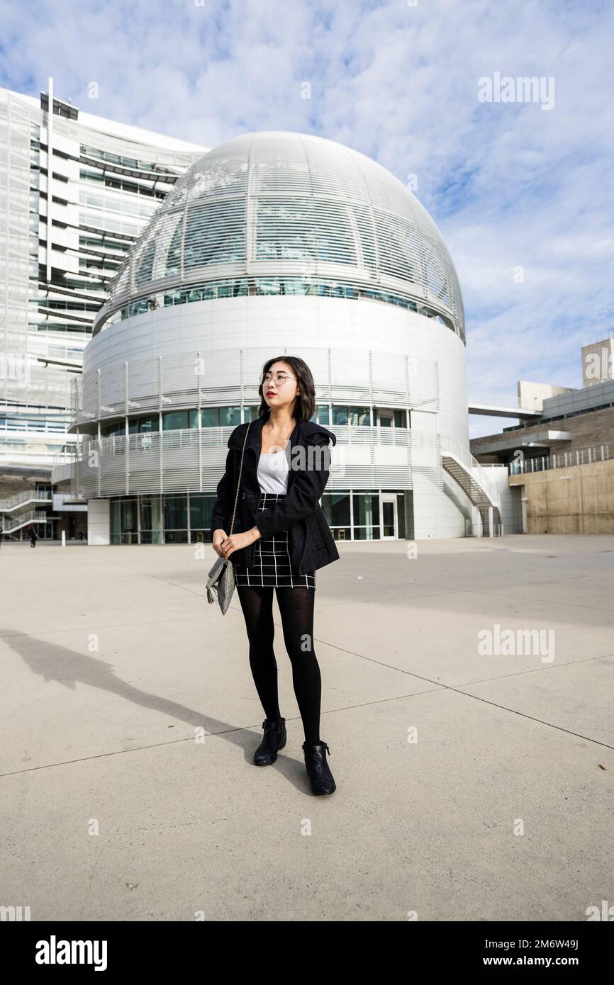 Junge Geschäftsfrau, die auf dem Betonplatz des modernen Gebäudes in der Innenstadt von San Jose spaziert Stockfoto