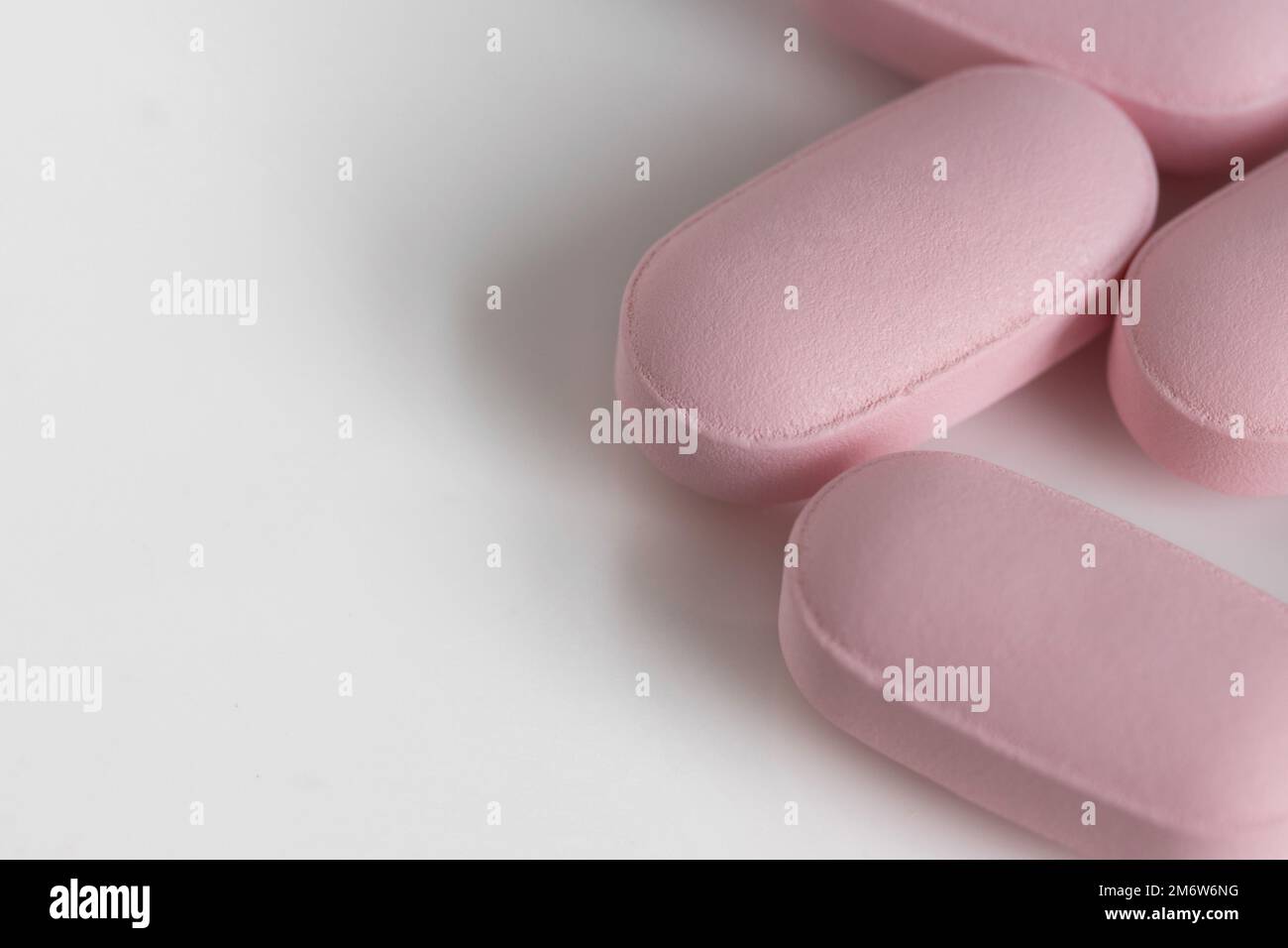 Nahaufnahme, Makroaufnahme von pinkfarbenen, länglichen Tablettentabletten auf weißem Hintergrund mit Kopierbereich und geringer Schärfentiefe Stockfoto