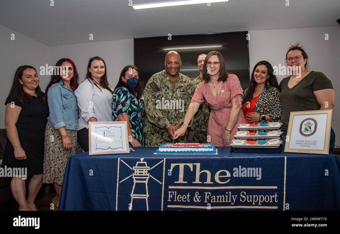 Captain David Adams, Commander, Fleet Activities Sasebo (CFAS), und Paige Alewine, CFAS Ombudsman, schneiden einen Kuchen und posieren mit den Befehlshabern der Sasebo-Gegend und Mitarbeitern des Fleet and Family Support Center während einer Feier des Military Ehegatten Dankbarkeit Day im CFAS Nimitz Park USO am 6. Mai 2022. Am Freitag vor dem Muttertag wird der „Witwe Honoration Day“ gefeiert, der die wichtige Rolle der Militärehelichte in den Streitkräften der Vereinigten Staaten würdigt. Stockfoto