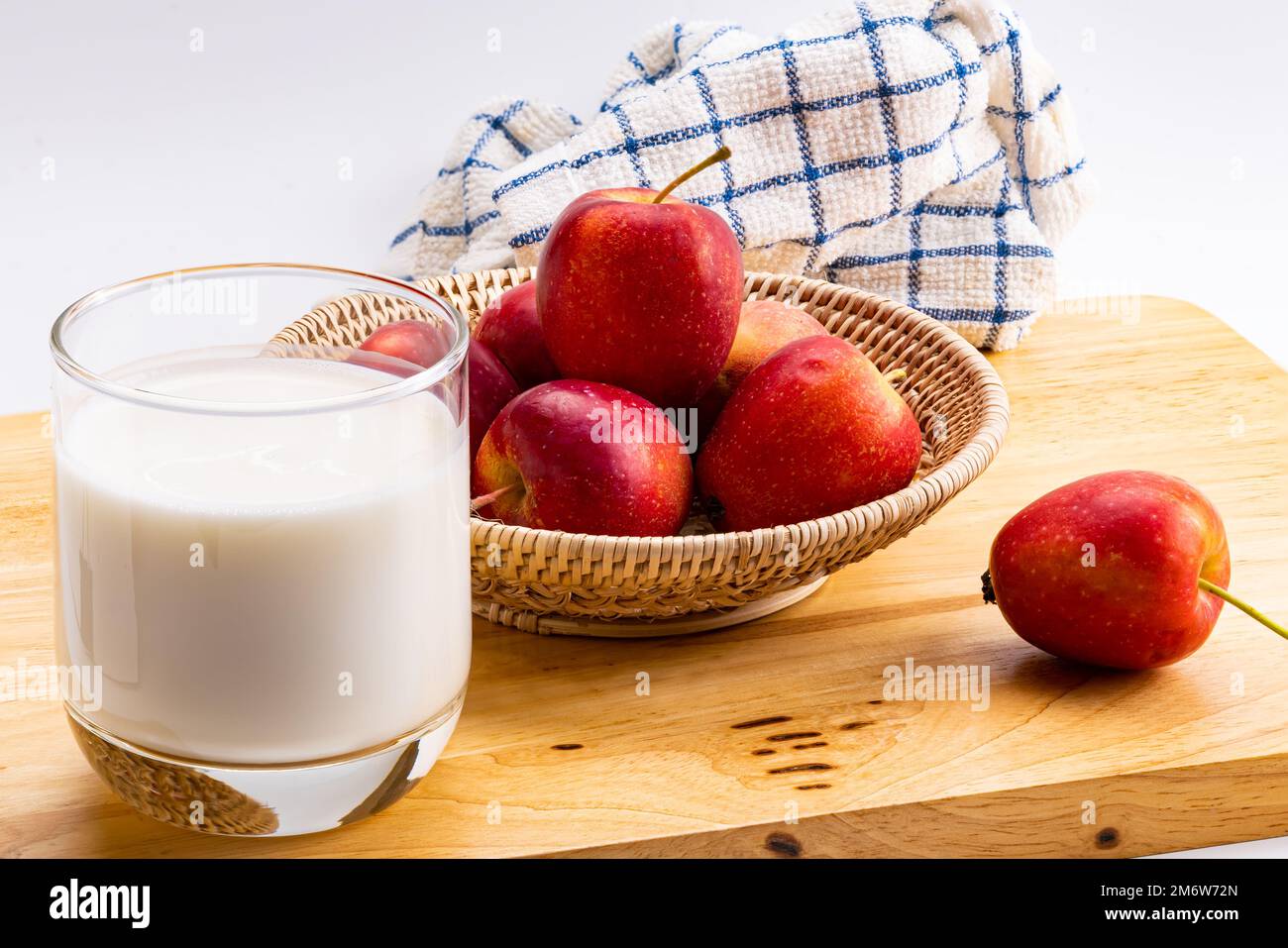 Seitenansicht, ein Glas frische Milch mit frischem Mini-Apfel in einem Bambus-Tablett. Stockfoto