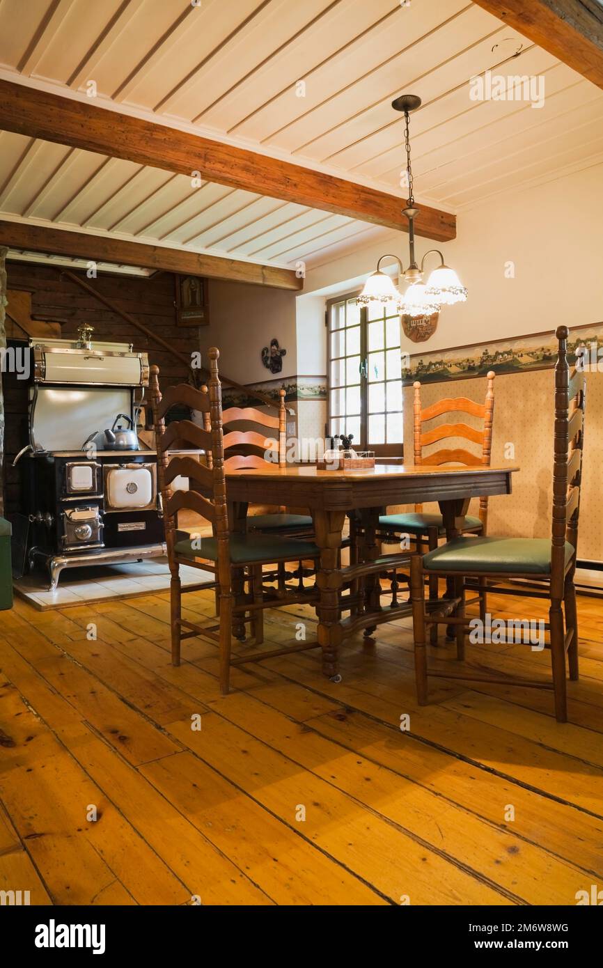 Antiker Holztisch und Stühle mit hoher Rückenlehne, 1850er Jahre Sweet Heart Retro-Kochherd handgefertigt von Elmira Herd arbeitet in der Küche im Blockhaus. Stockfoto