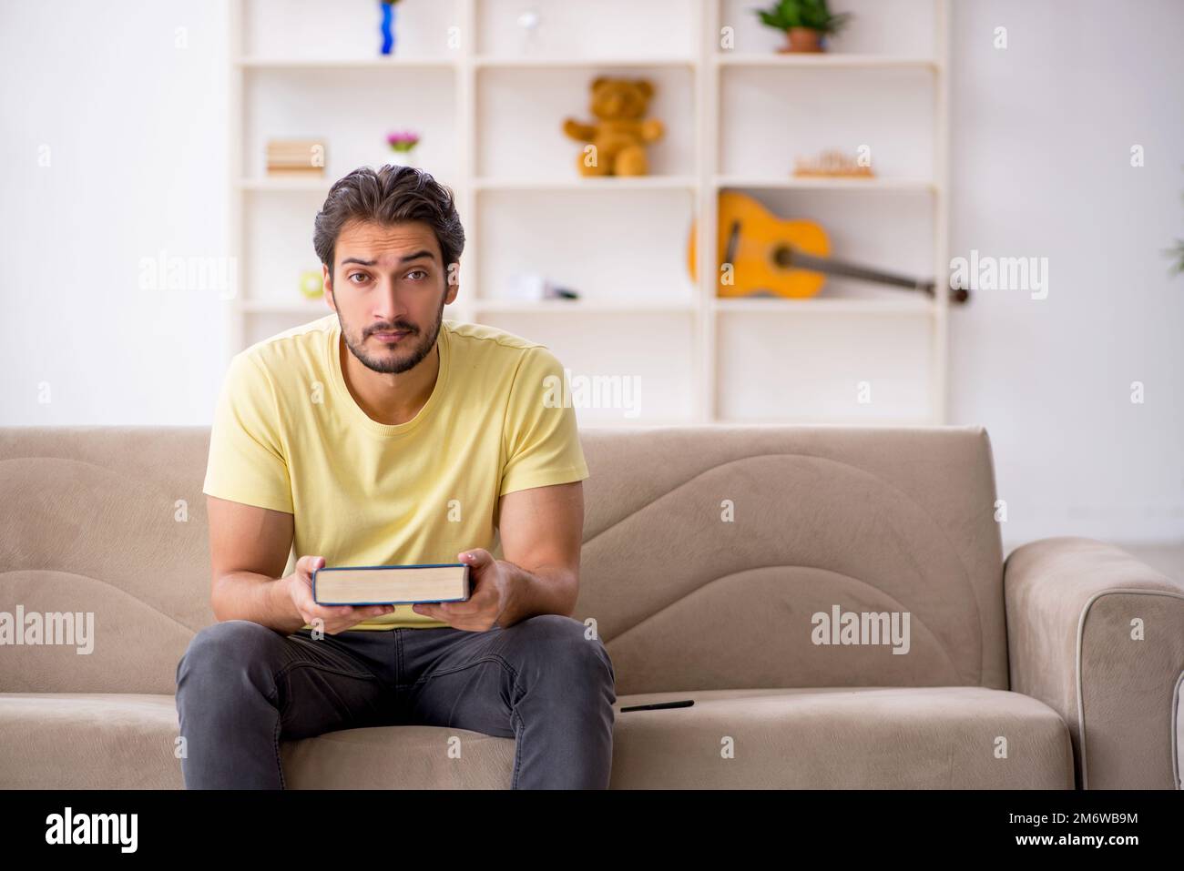 Junger Mann liest zu Hause Buch während einer Pandemie Stockfoto