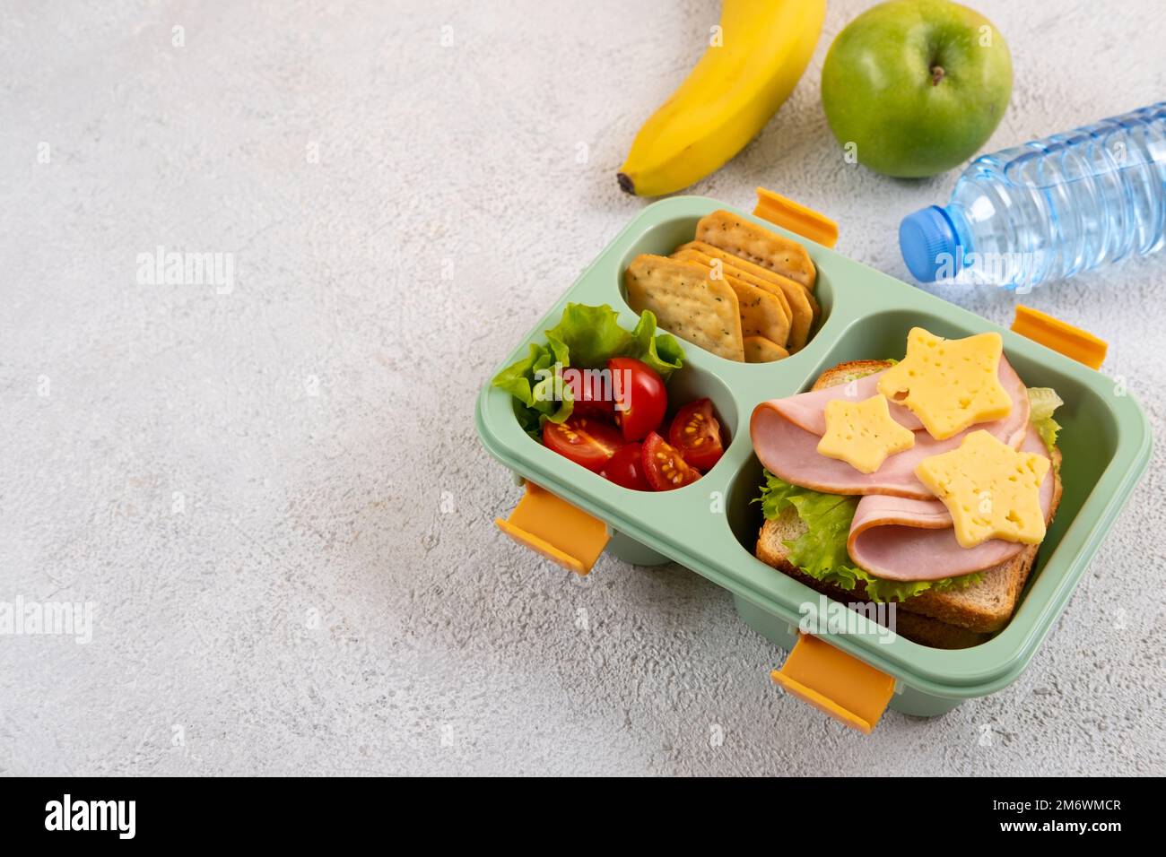 Gesunde Schule Lunchbox mit Sandwich und Salat auf dem Tisch. Banane, Apfel und eine Flasche Wasser. Zurück in die Schule Stockfoto