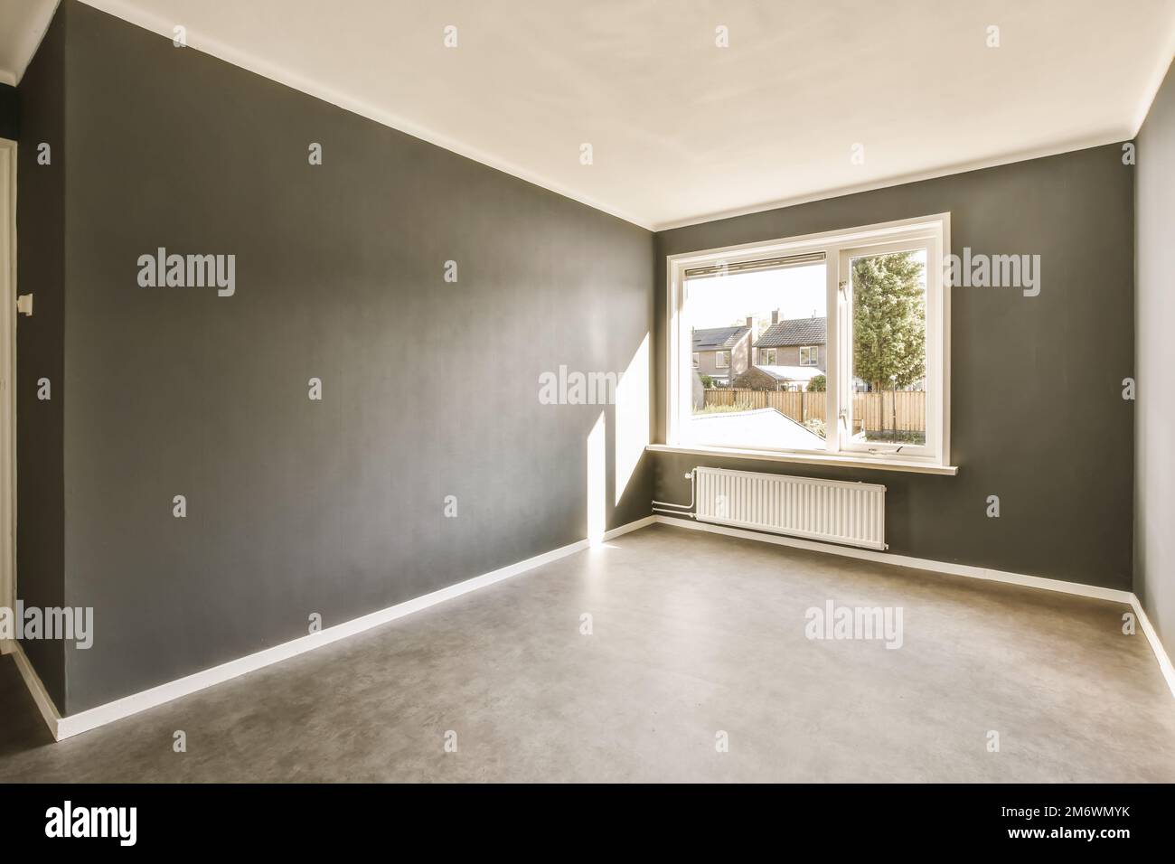 Ein leeres Wohnzimmer mit dunkelgrauen Wänden und weißen Verzierungen an den Wänden, es gibt ein radiales Fenster Stockfoto