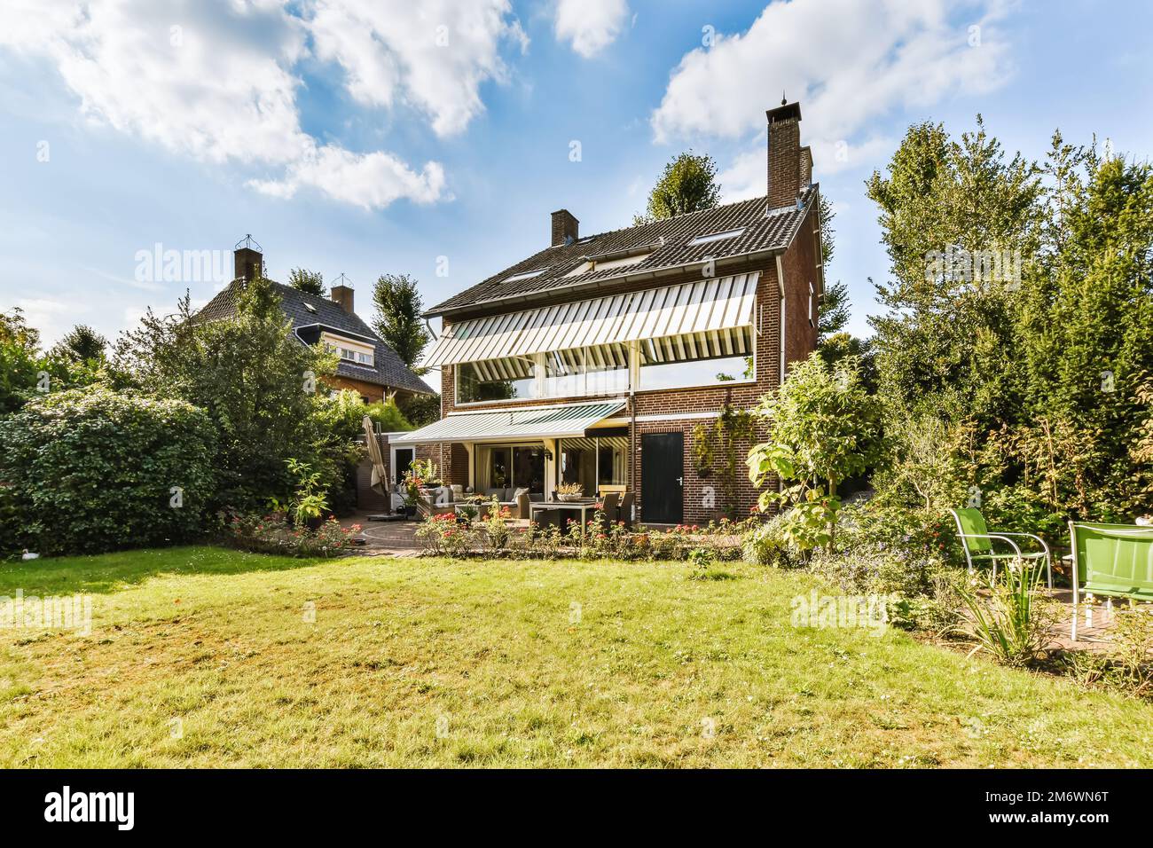 Ein Haus, das sich in der Mitte einer Gegend mit grünem Gras und Bäumen auf beiden Seiten des Hauses befindet Stockfoto