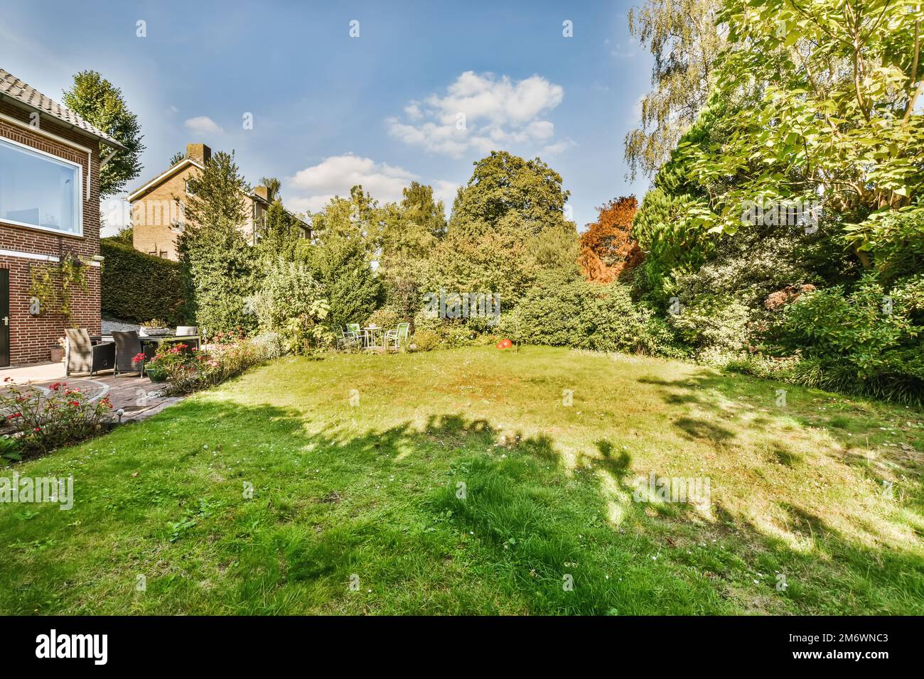Ein Hinterhof mit Gras, Bäumen und Büschen im Vordergrund ist auf der rechten Seite des Fotos sichtbar Stockfoto