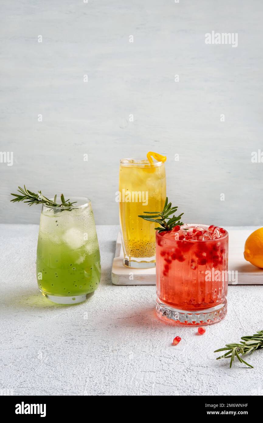 Drei farbenfrohe Sommercocktails in Gläsern auf einem weißen Tisch. Auswahl an frischen Sommergetränken. Rote Sangria-Cocktails, Orangenpunsch Stockfoto