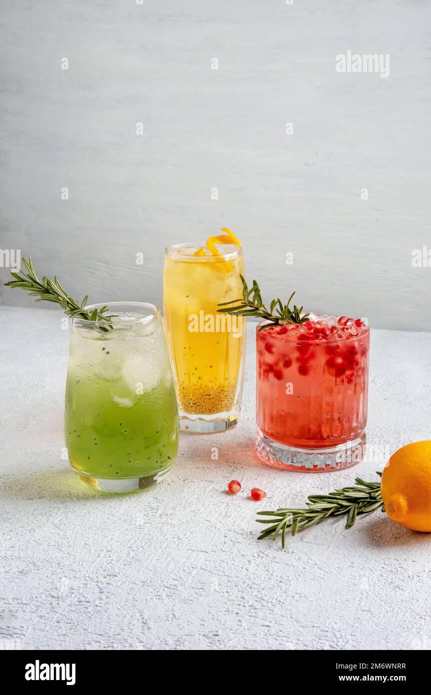 Drei farbenfrohe Sommercocktails in Gläsern auf einem weißen Tisch. Auswahl an frischen Sommergetränken. Rote Sangria-Cocktails, Orangenpunsch Stockfoto