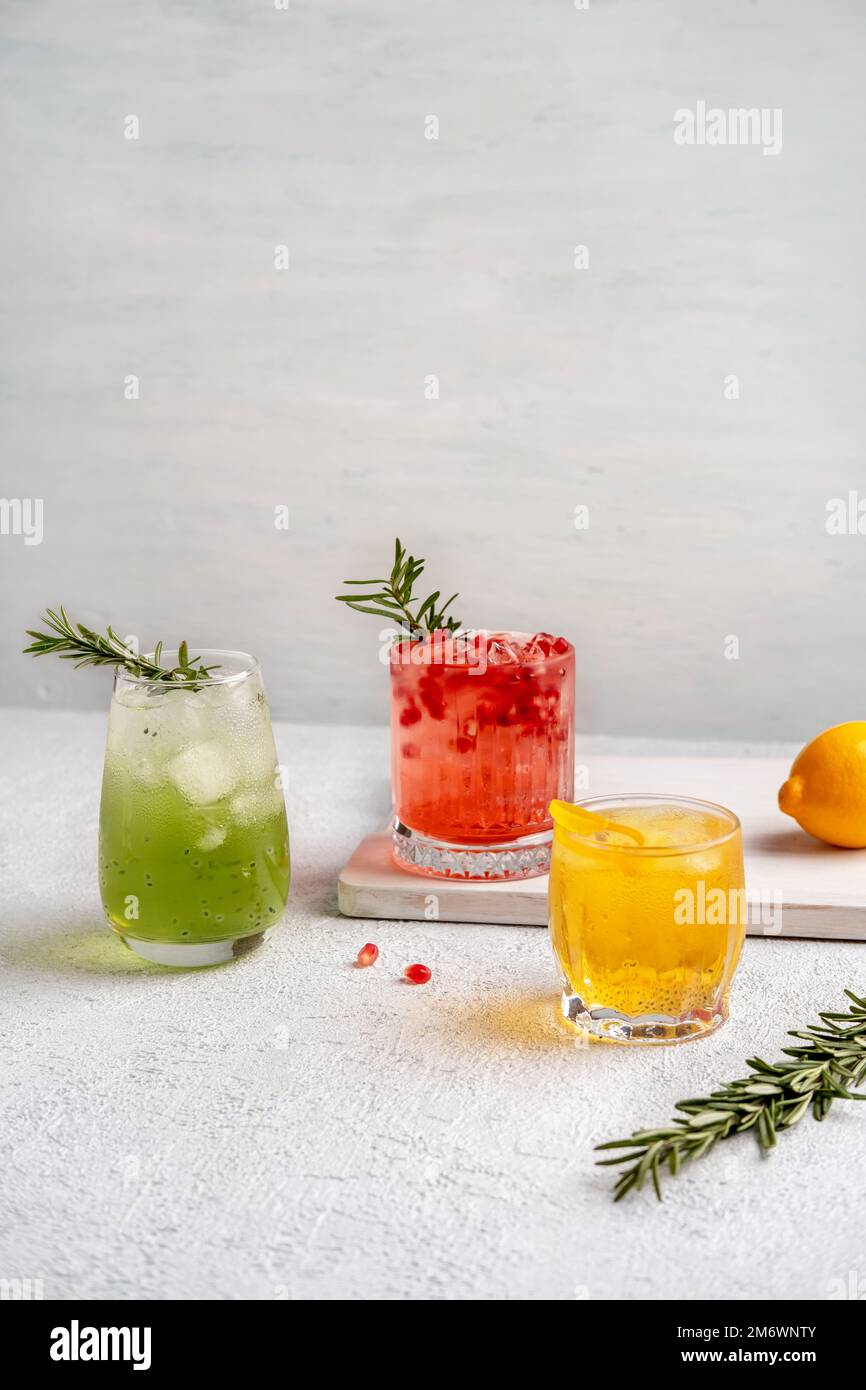 Drei farbenfrohe Sommercocktails in Gläsern auf einem weißen Tisch. Auswahl an frischen Sommergetränken. Rote Sangria-Cocktails, Orangenpunsch Stockfoto